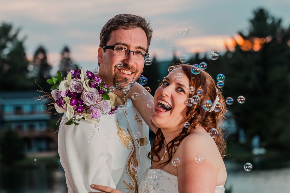 Photographie de mariage par Mathieu Breton : Louis et son épouse souriants avec bouquet et bulles de savon.
