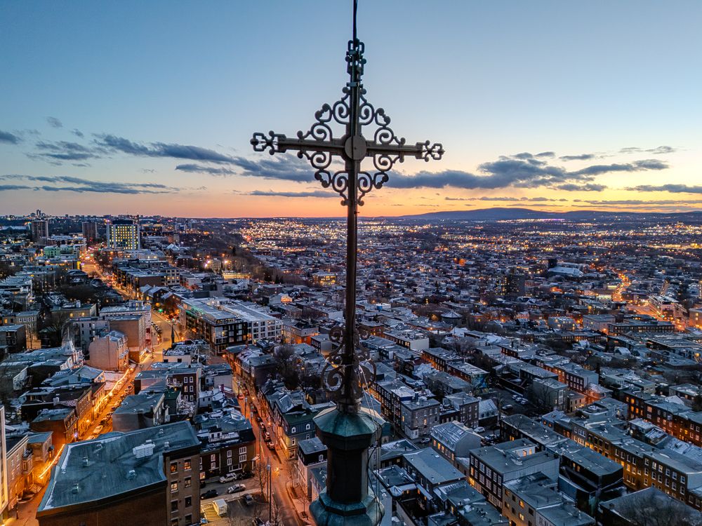 Vue aérienne d’une croix d’église dominant une ville au coucher du soleil, photo par drone de Mathieu Breton.