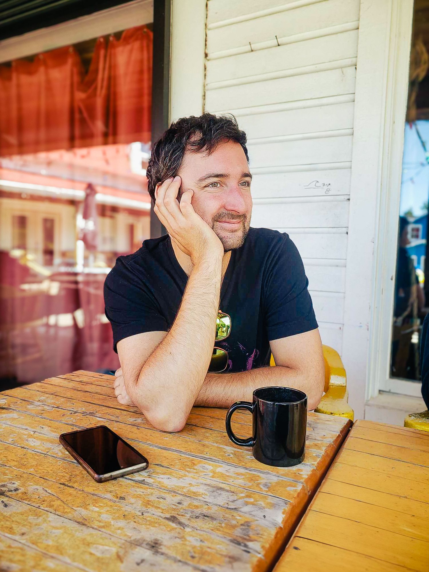Portrait lifestyle de Mathieu Breton, photographe à La Gaude, assis en terrasse avec une tasse de café.