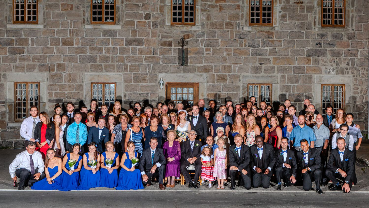 Photo de mariage par Mathieu Breton : photo de groupe des invités devant un mur de pierre.