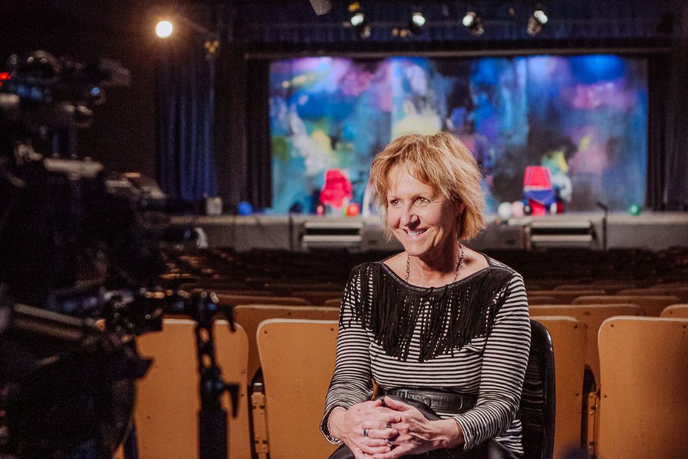 Photographie culturelle par Mathieu Breton : actrice posant dans un théâtre avec décors colorés en arrière-plan.
