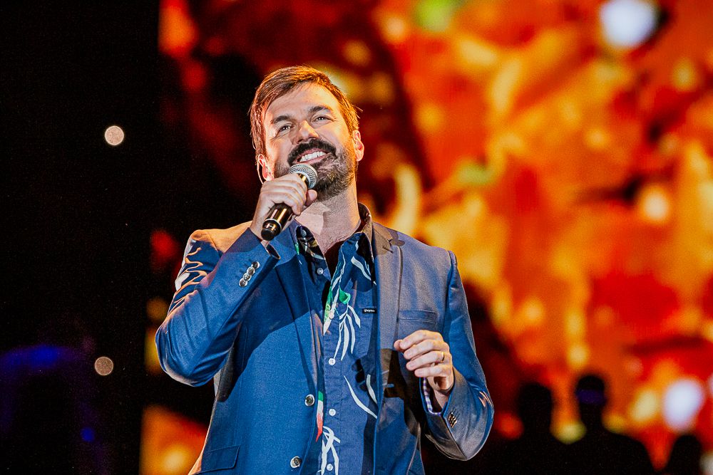 Photographie de concert par Mathieu Breton : Damien chantant sur scène devant un écran flamboyant.
