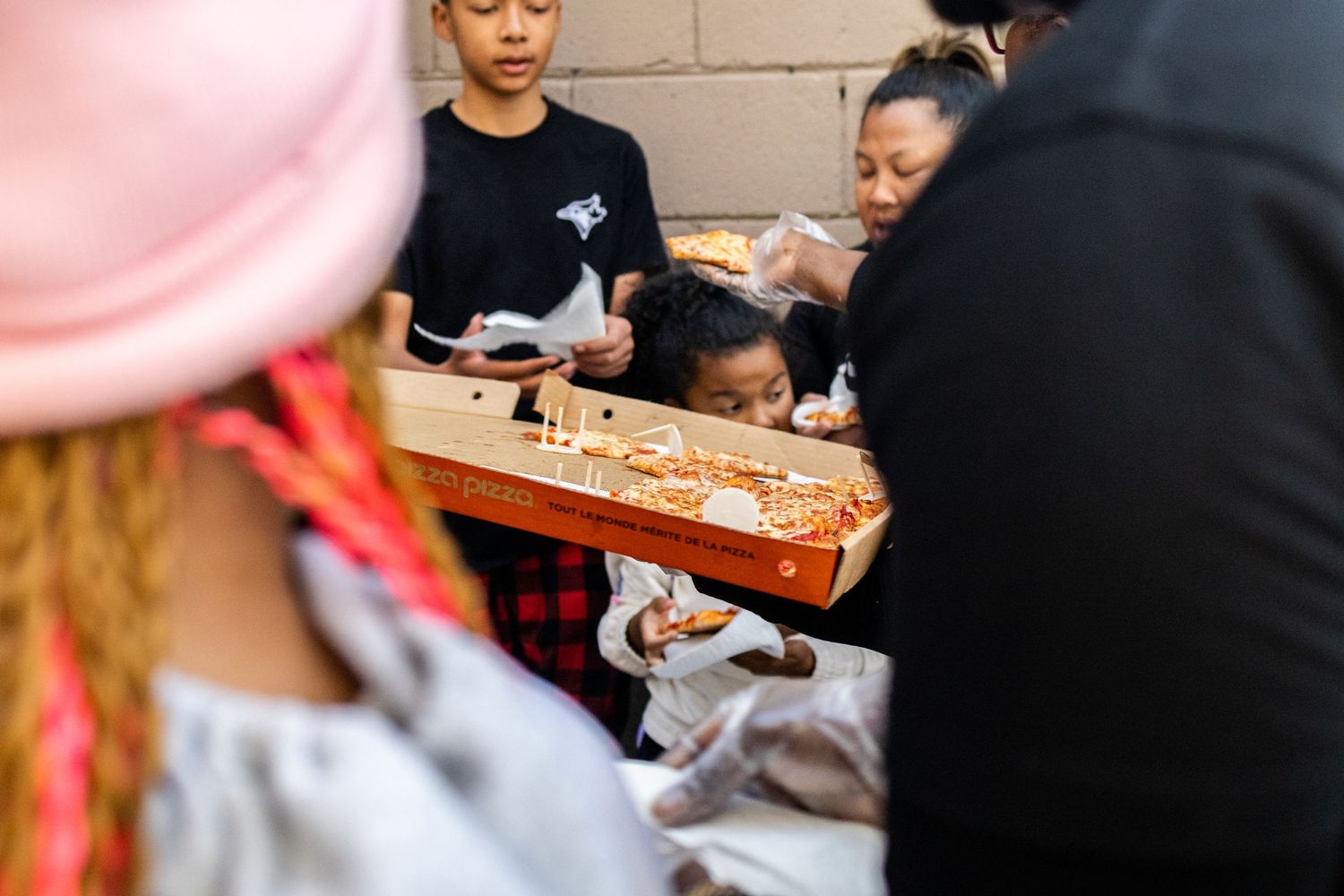 Pizza boxes being distributed at a community event under a covered area.