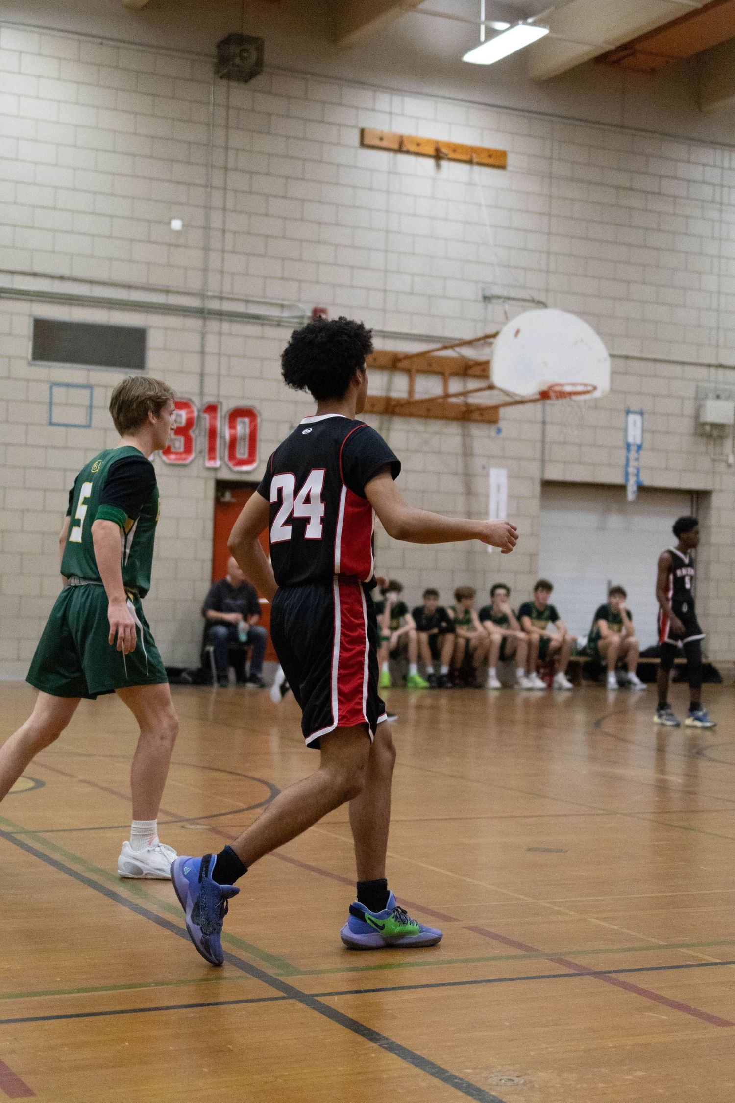 Basketball players compete in indoor gymnasium during game.