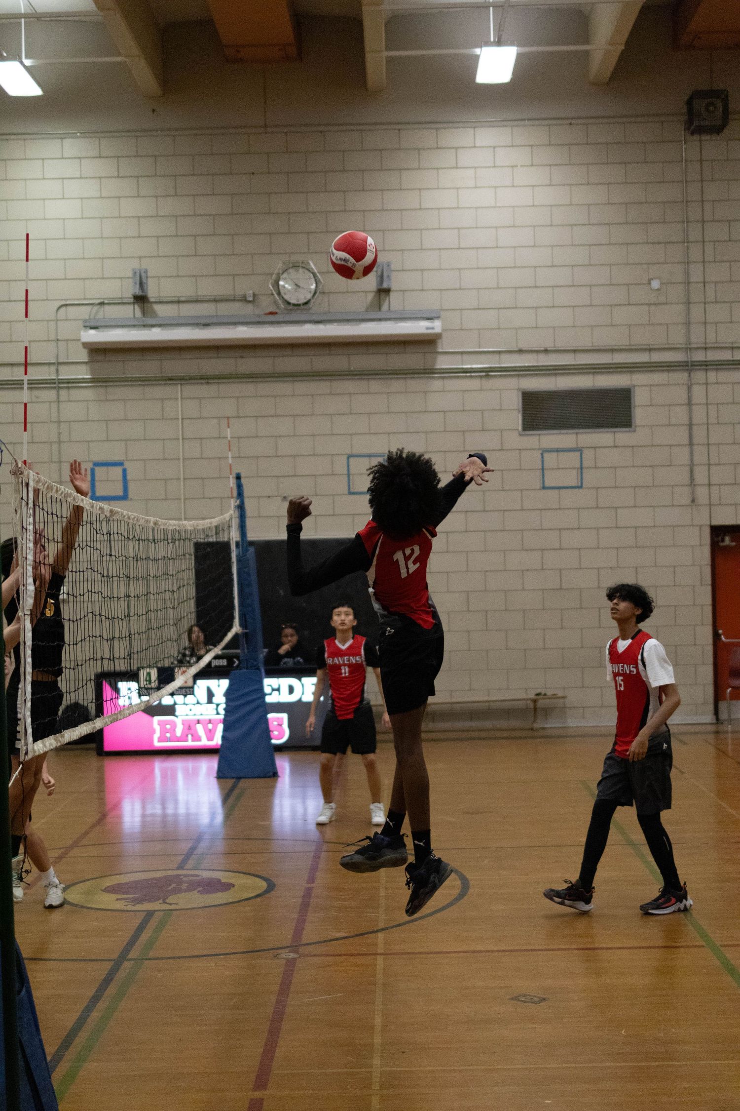 Volleyball player jumping high to spike the ball during an indoor game.