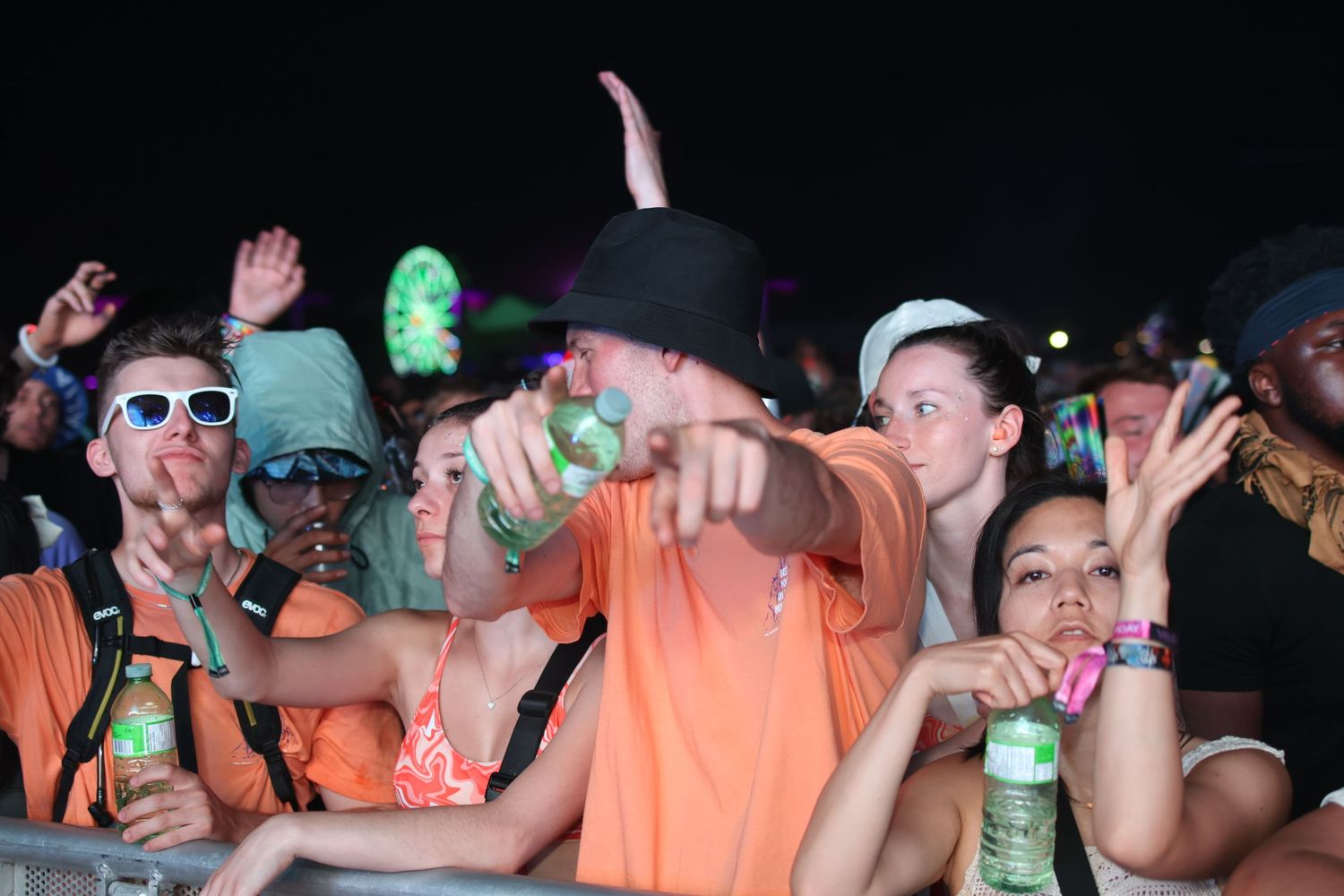 Energetic crowd celebrating at outdoor music festival with glowing lights.