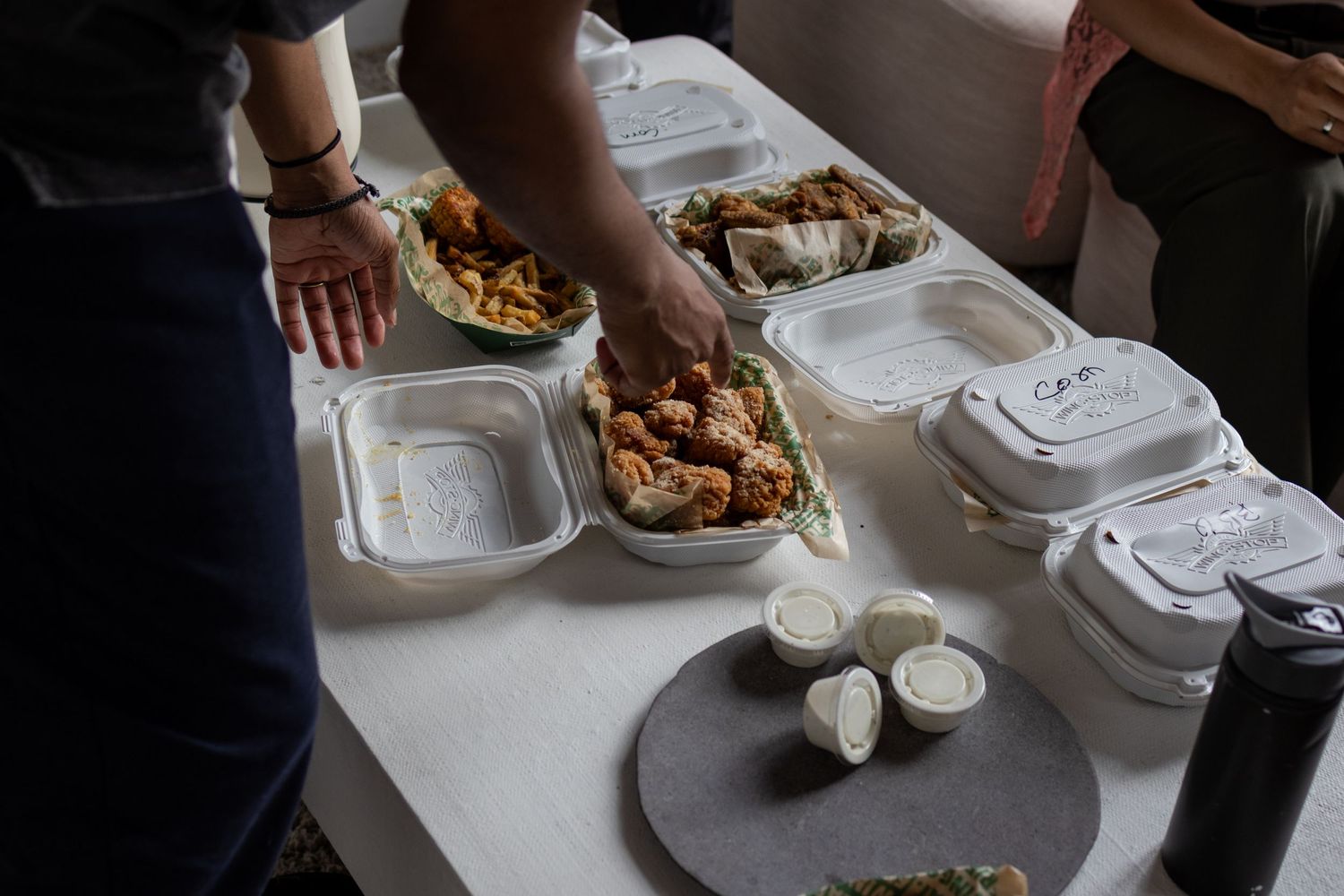 Food service setup with takeout containers and plates on a white table.