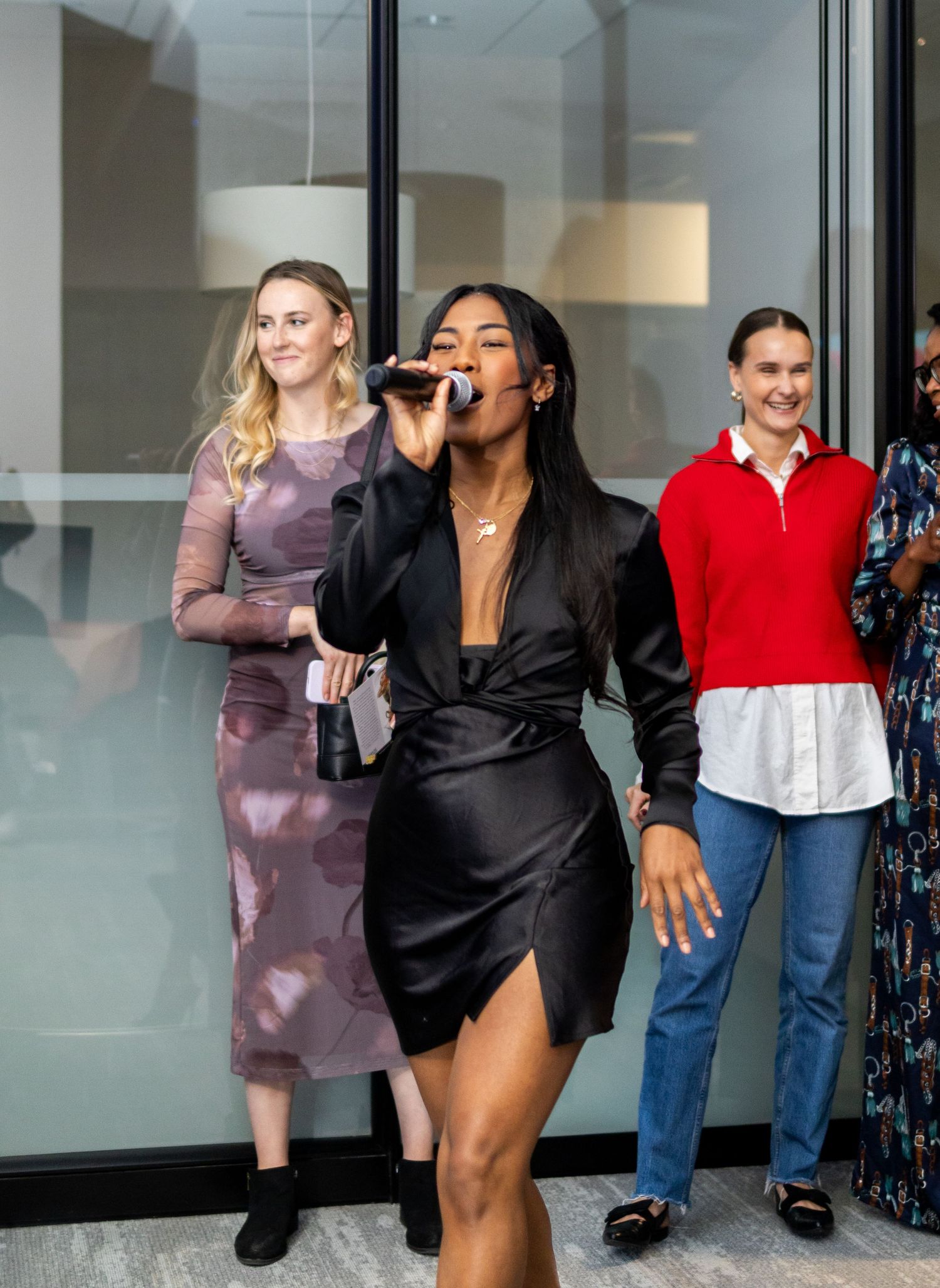 Performers entertain audience in modern venue with glass walls.