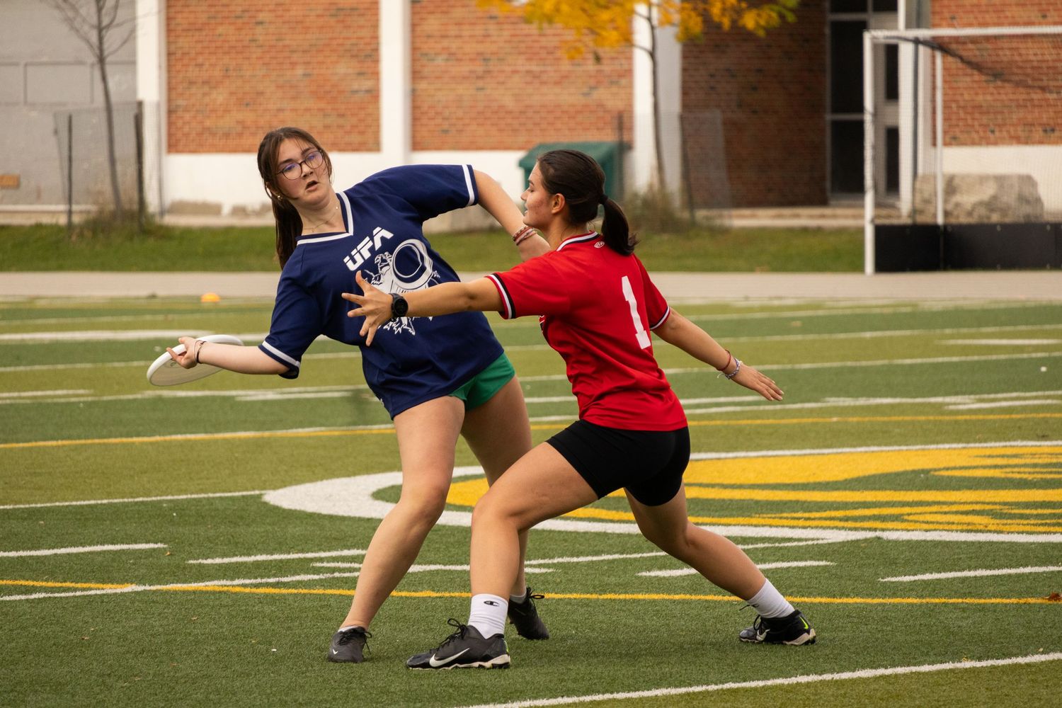 Ultimate frisbee players compete on sports field during intense game action.