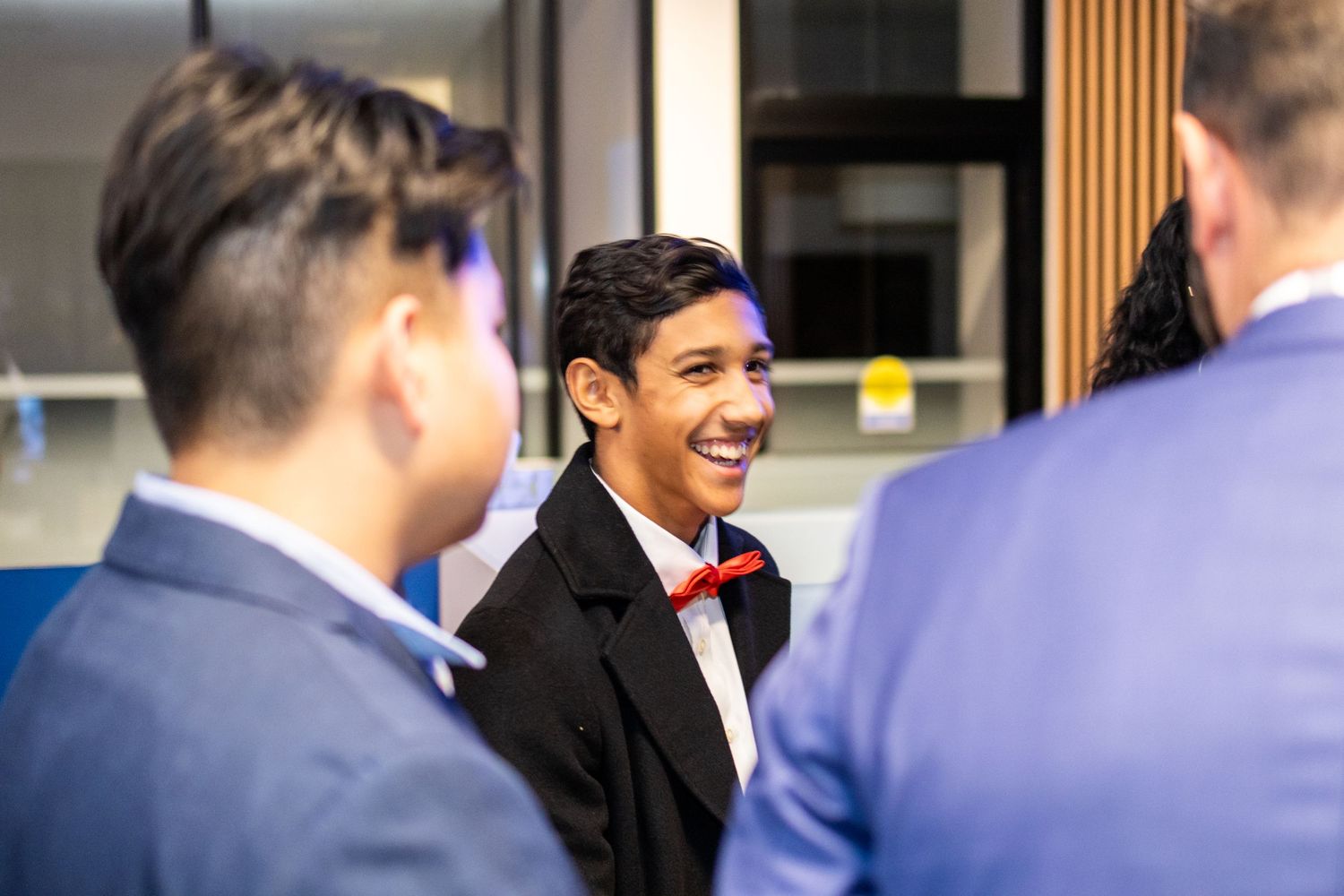Young professional in suit and bow tie smiles during business conversation.