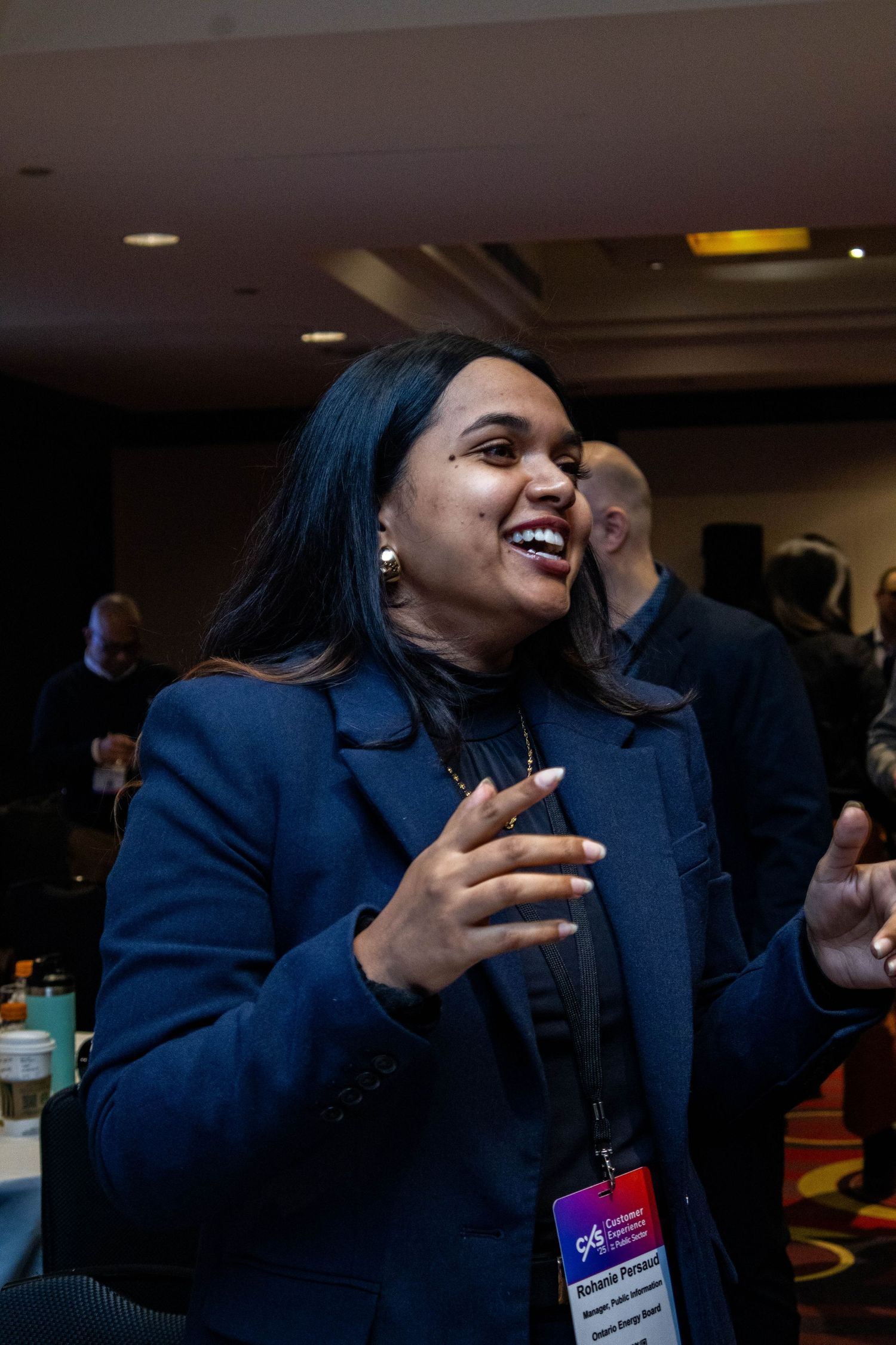 Professional in navy blazer speaks animatedly during business conference.