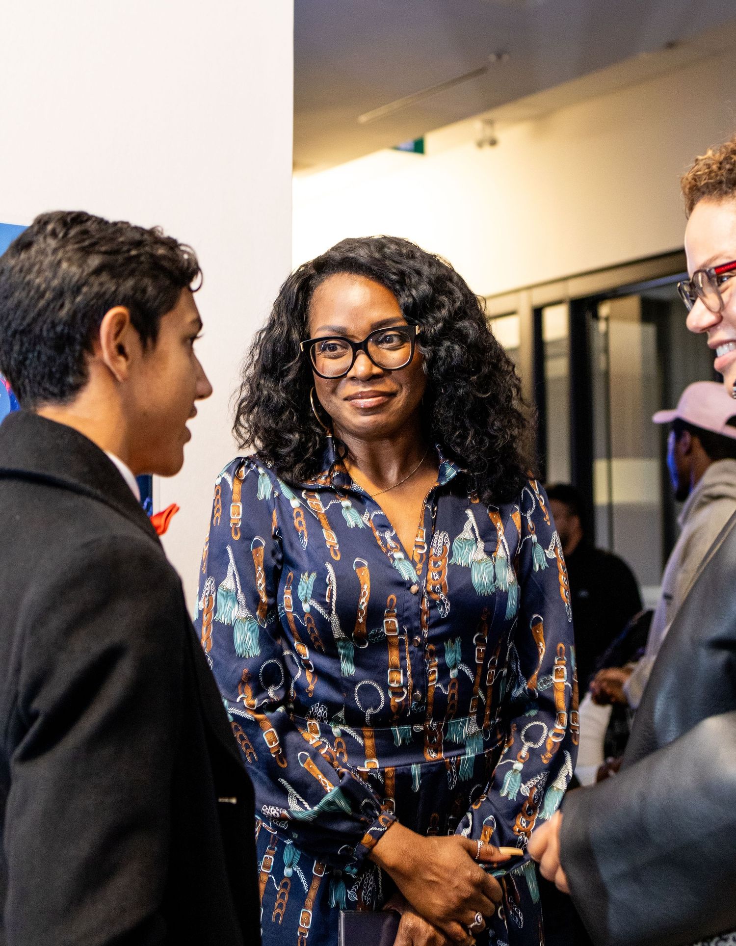 Group of professionals engage in friendly conversation at indoor networking event.
