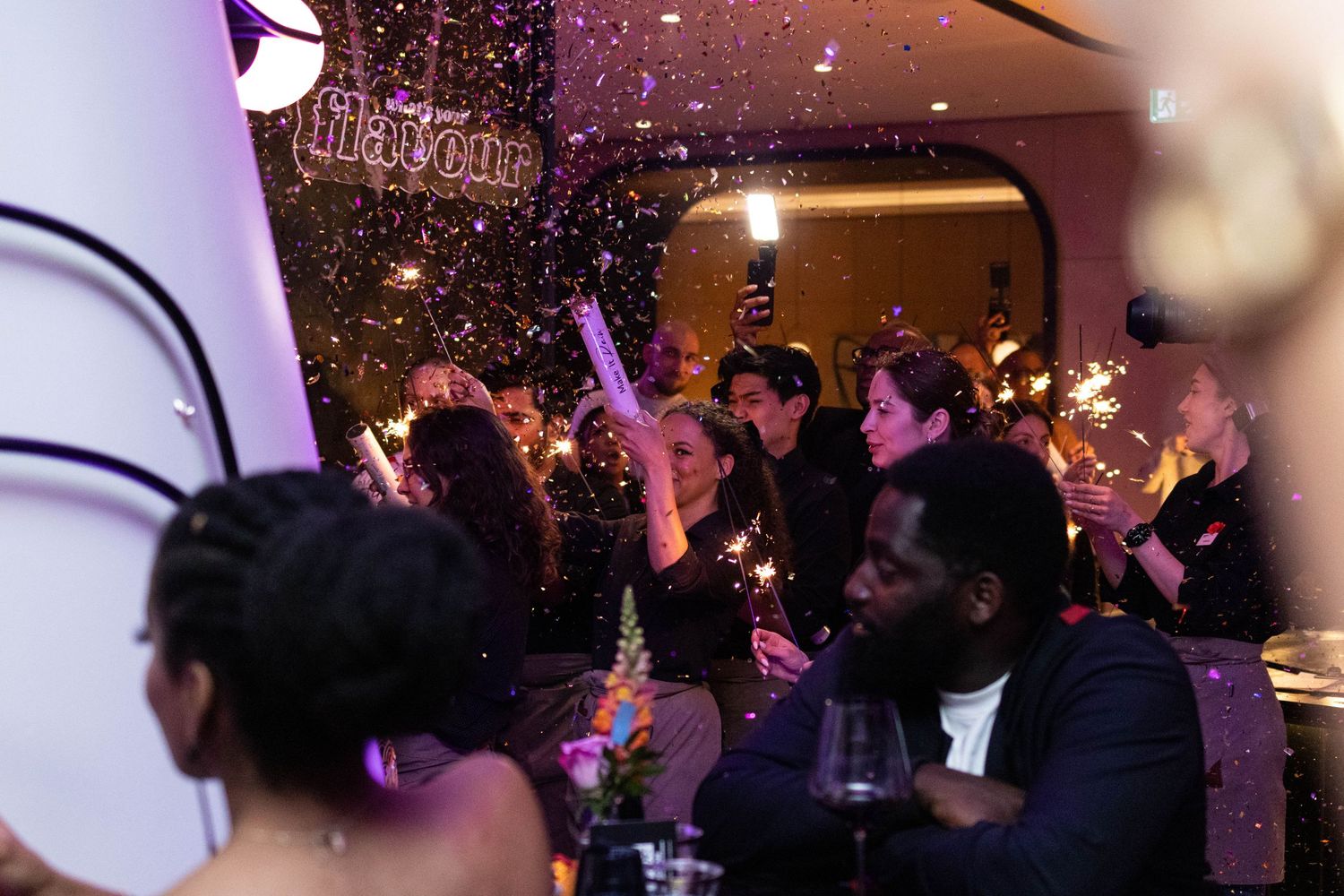 Lively nightclub scene with purple lighting and crowd dancing under disco lights.