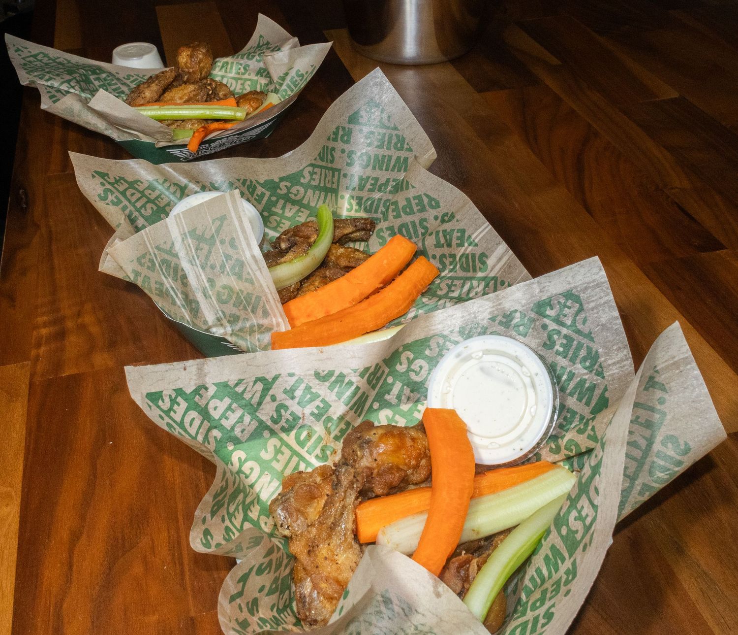 Fresh wings with celery, carrots and dipping sauce served on wax paper at a restaurant.