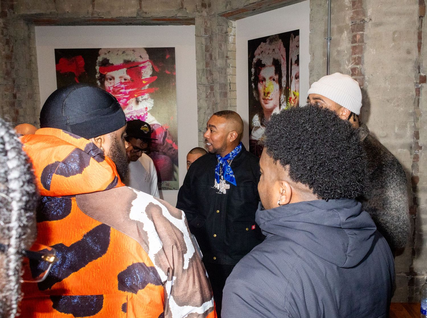 People gathered in brick-walled gallery space viewing artwork.