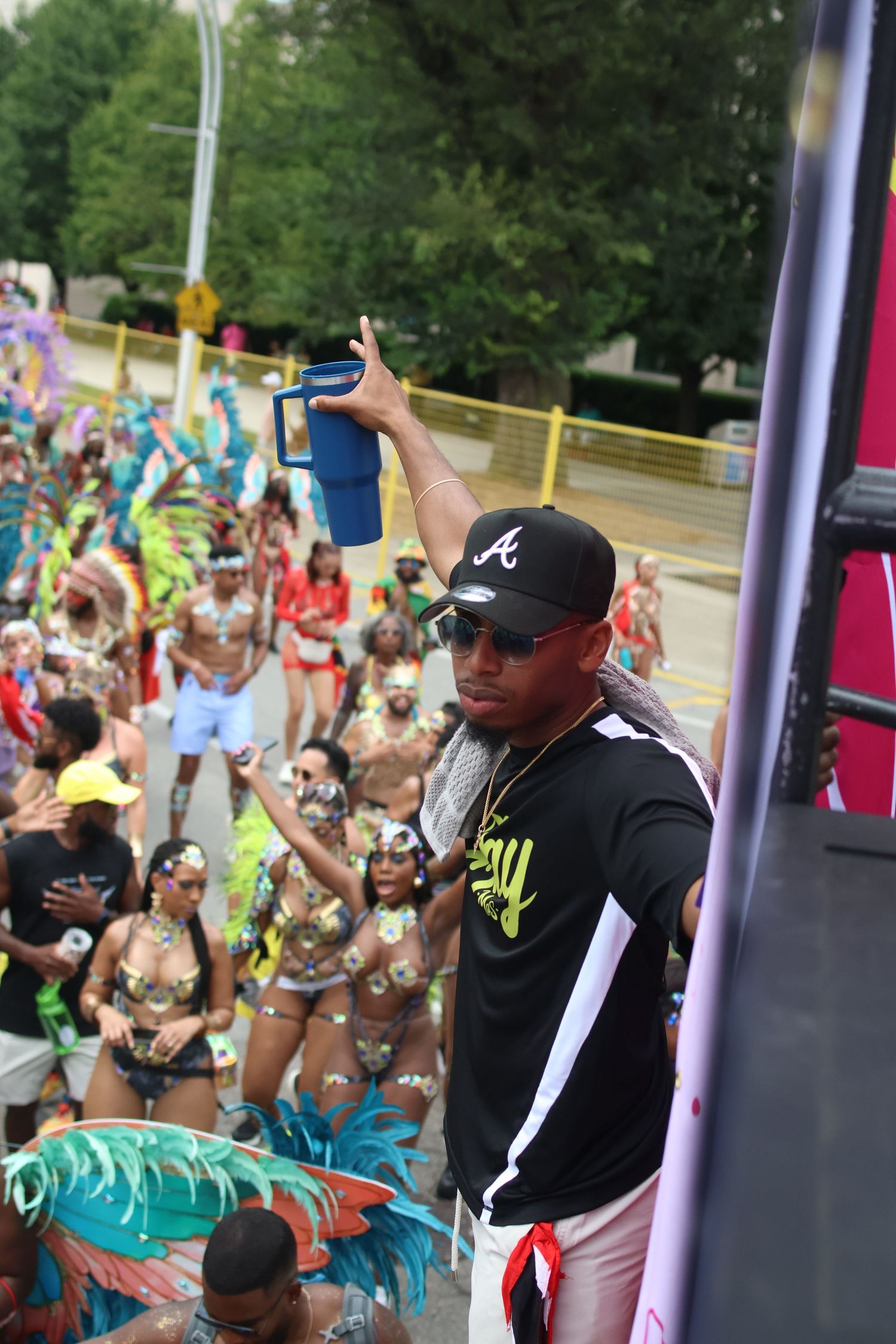 DJ in black shirt and baseball cap performs for crowd at outdoor festival.