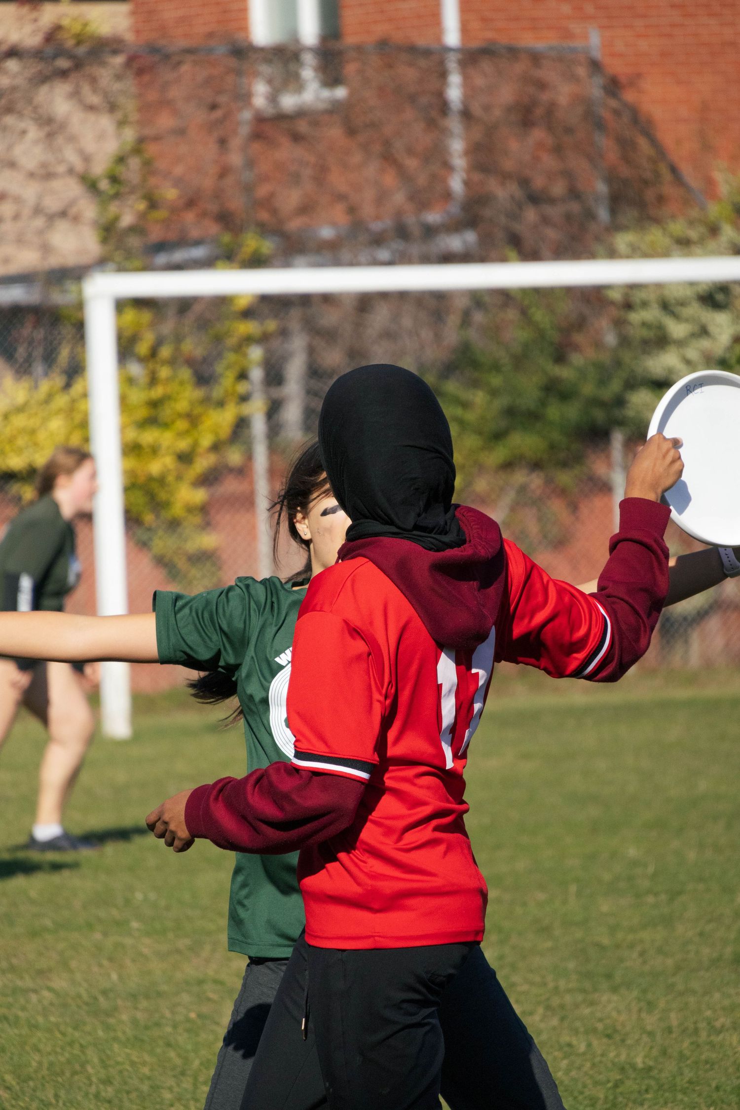 Players in action during outdoor sports match with goal post visible.
