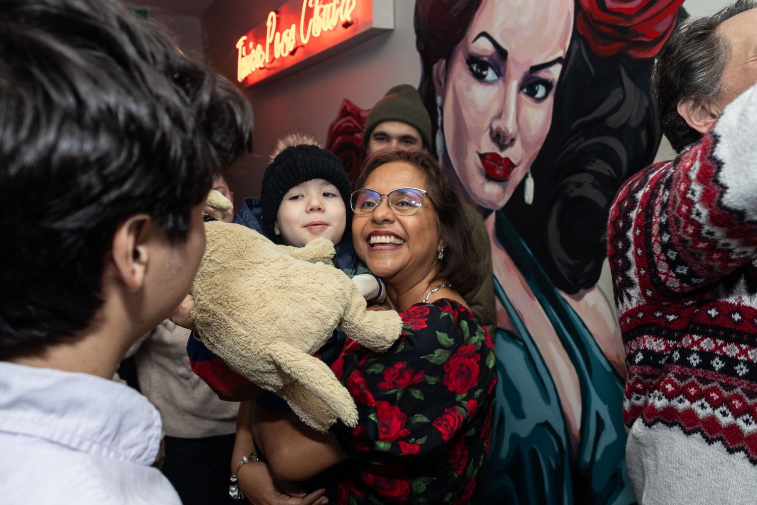 Happy gathering with stuffed animal at venue with decorative wall art.