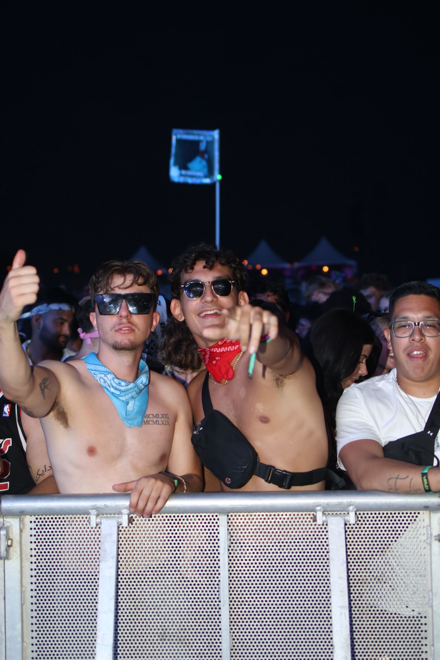 Enthusiastic festival attendees at metal barrier during nighttime outdoor concert.
