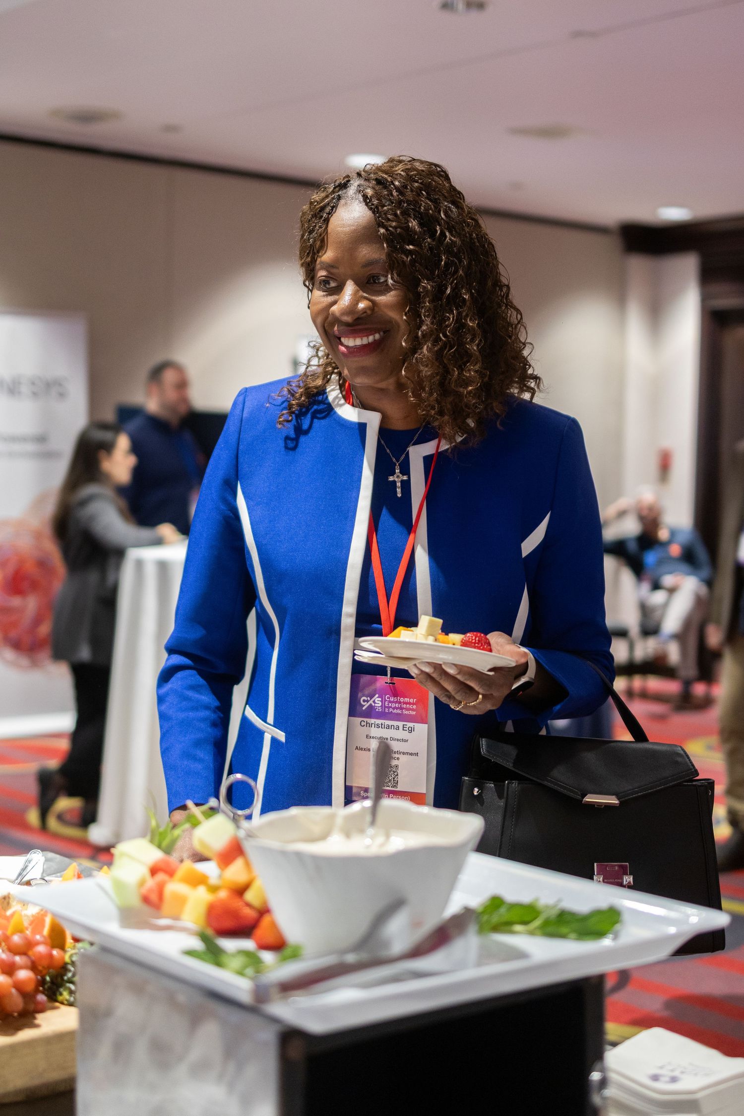 Attendee in royal blue blazer selects food from buffet at professional conference.