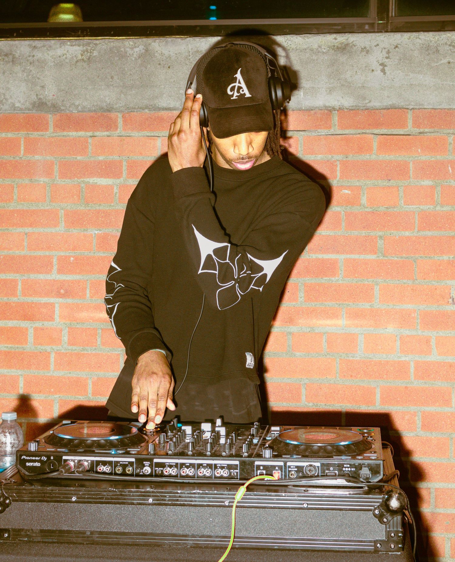 DJ in dark clothing mixing music on turntables during nighttime performance.