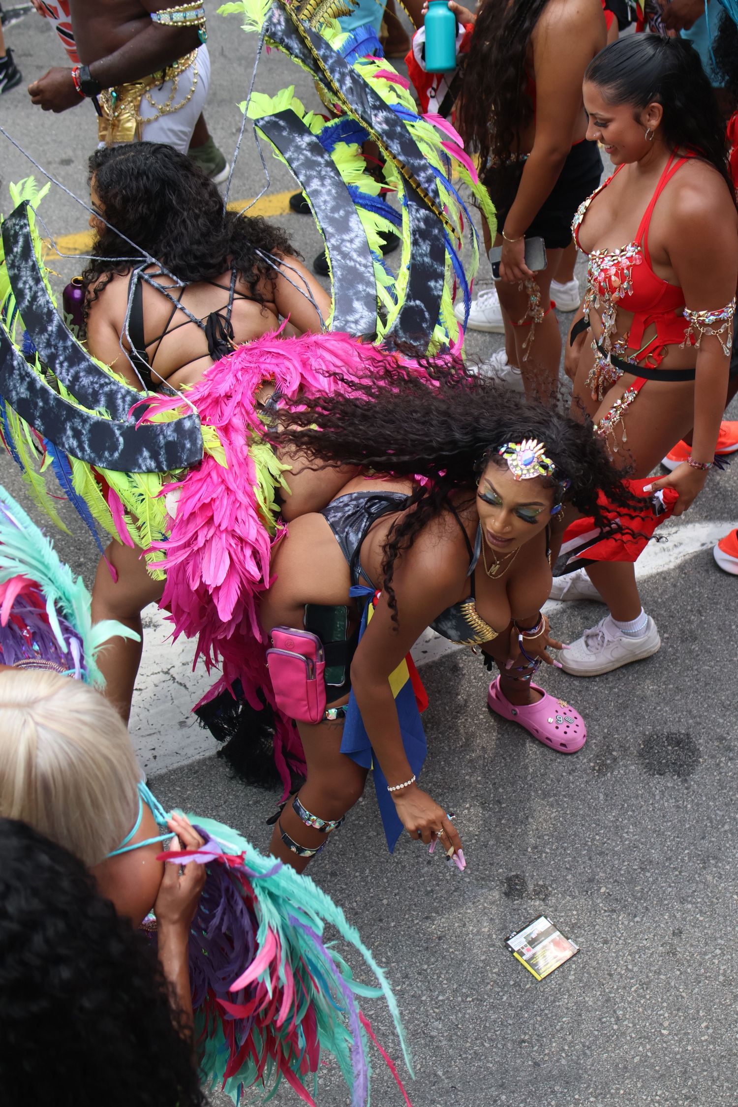 Festival dancers in colorful feathered costumes dance at street celebration.