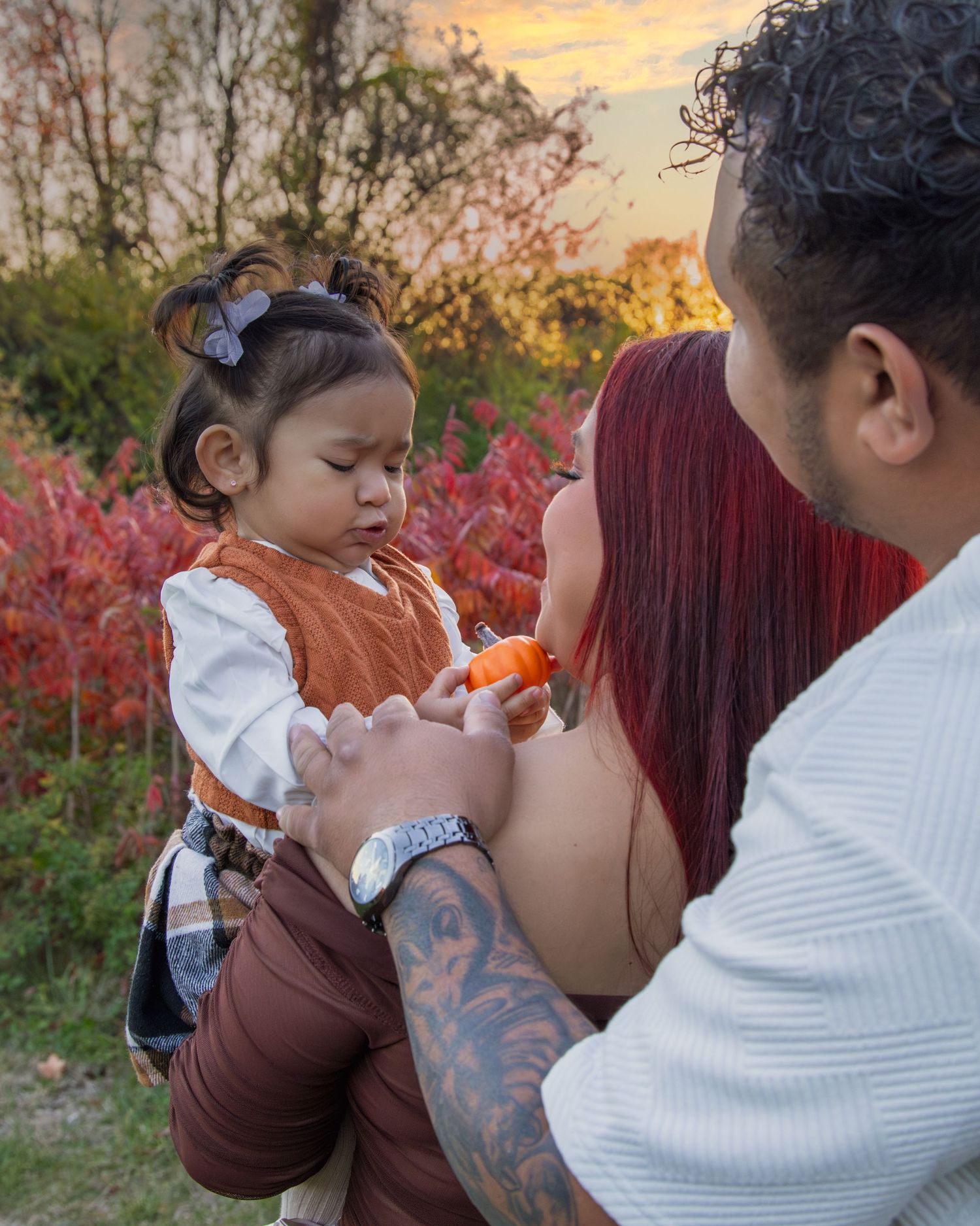 Intimate family moment captured during sunset with colorful fall foliage.