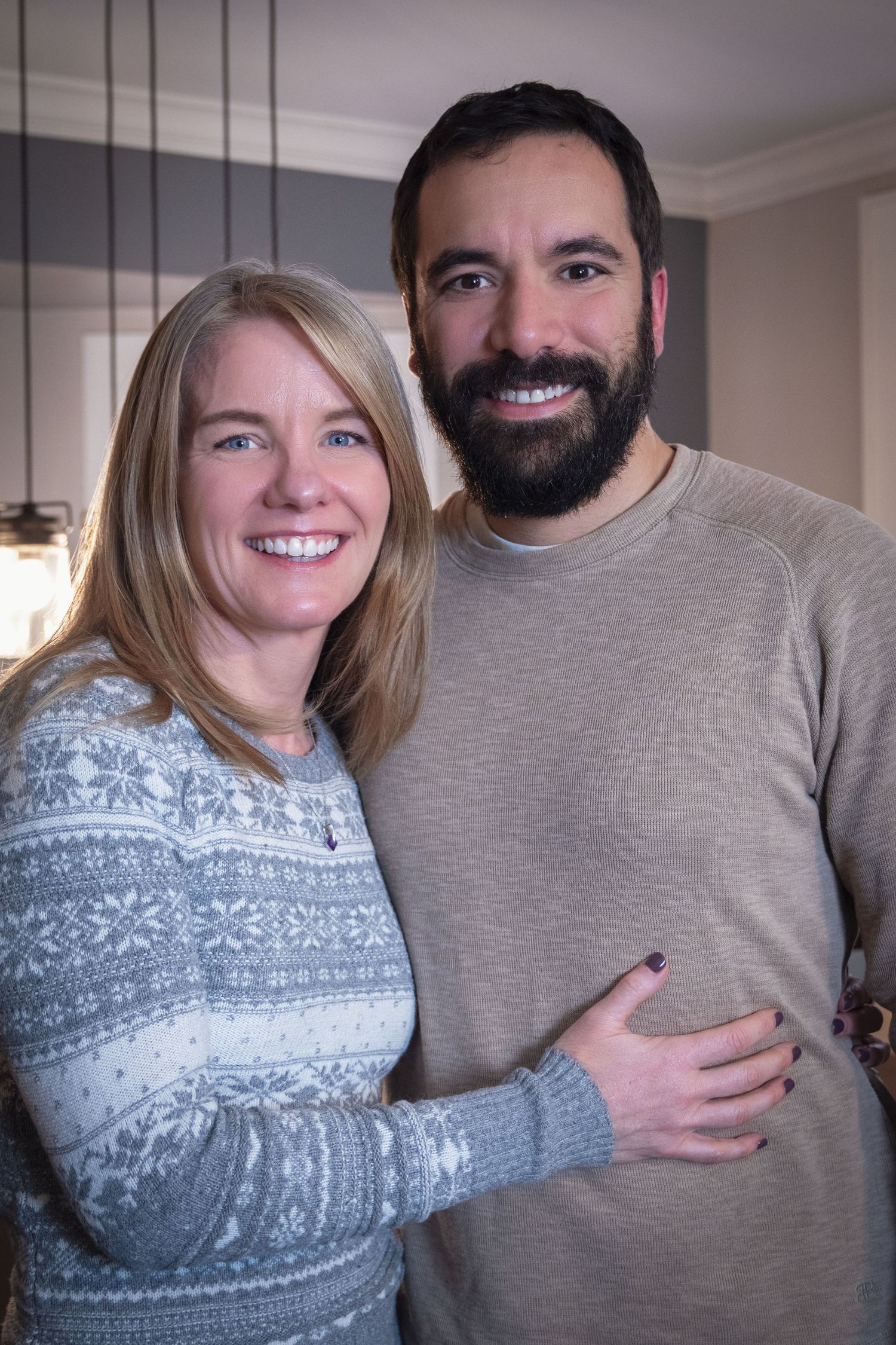 Happy couple in winter sweaters posing together indoors.