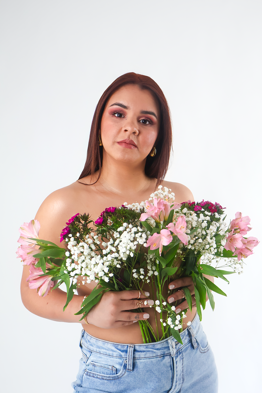 Fashion portrait with fresh spring flowers and distressed jeans against white backdrop.
