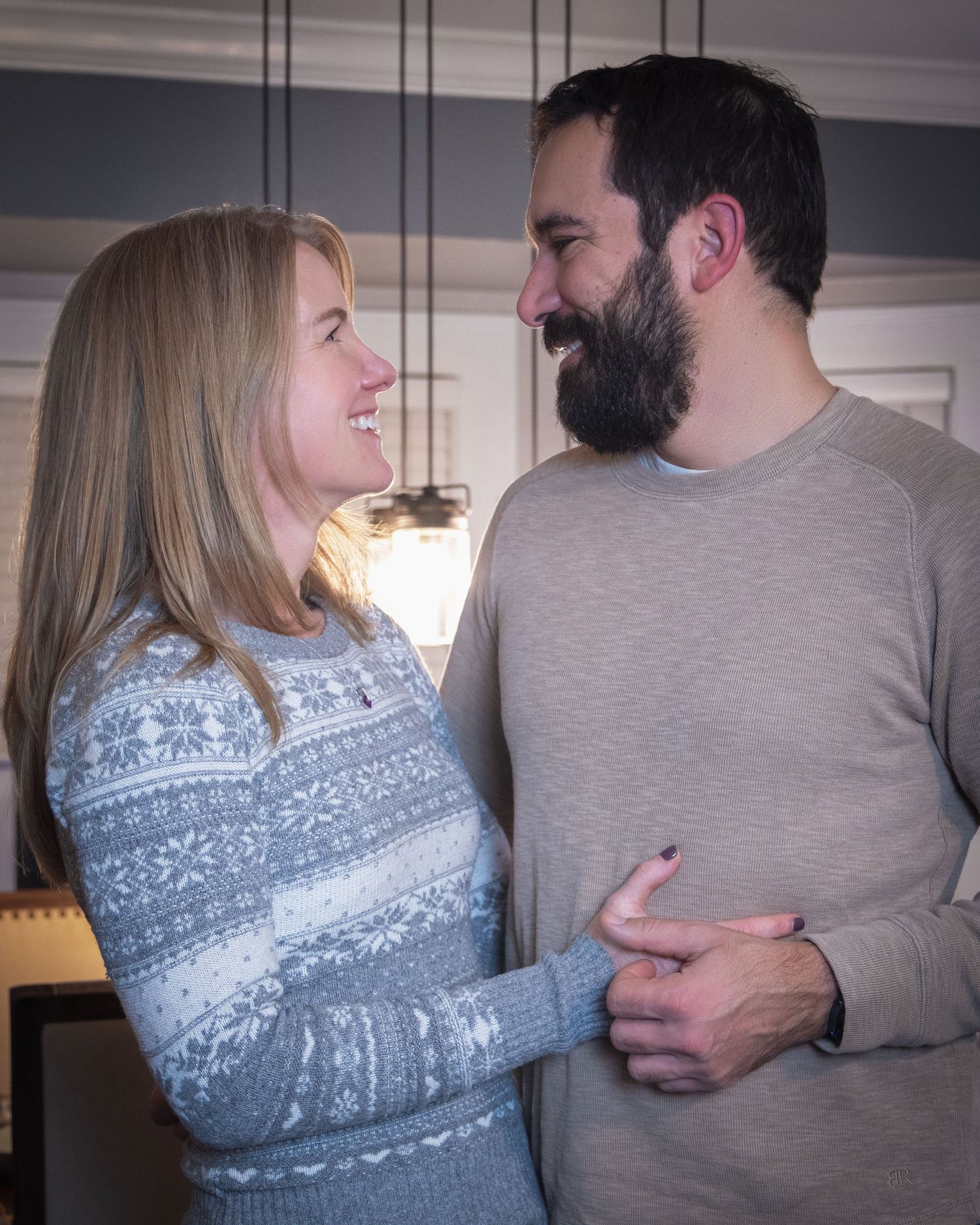 Couple sharing intimate moment while wearing cozy sweaters indoors.