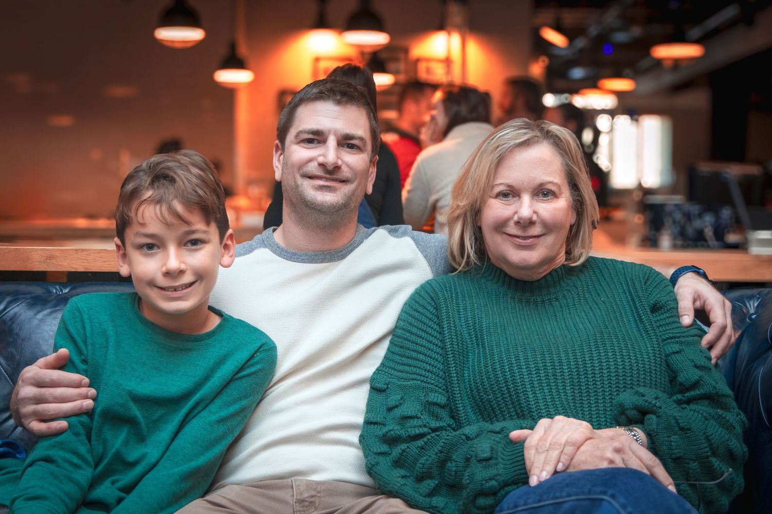 Three people sitting together on what appears to be a couch in an indoor setting.