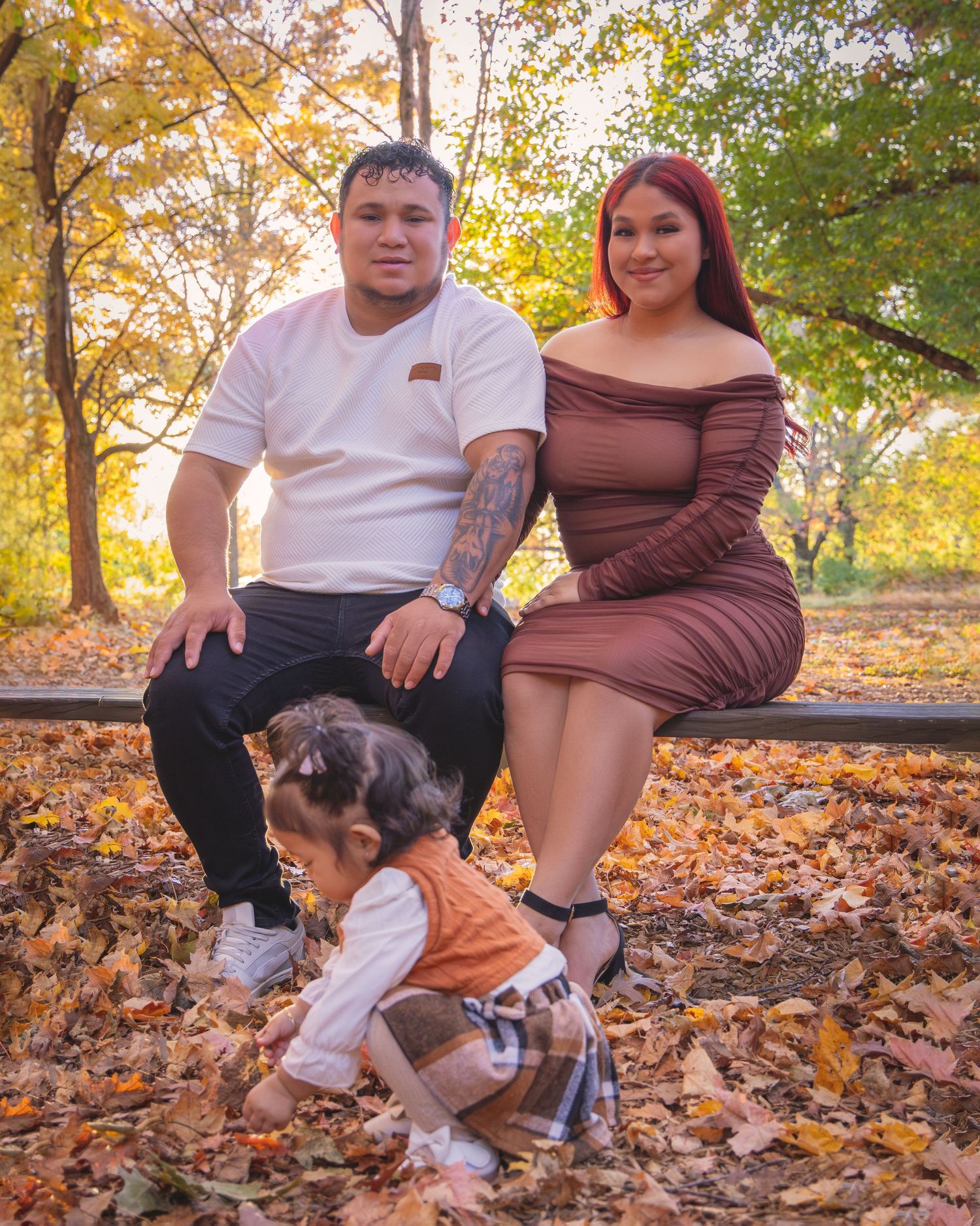 Family relaxing on wooden bench in park during autumn season.