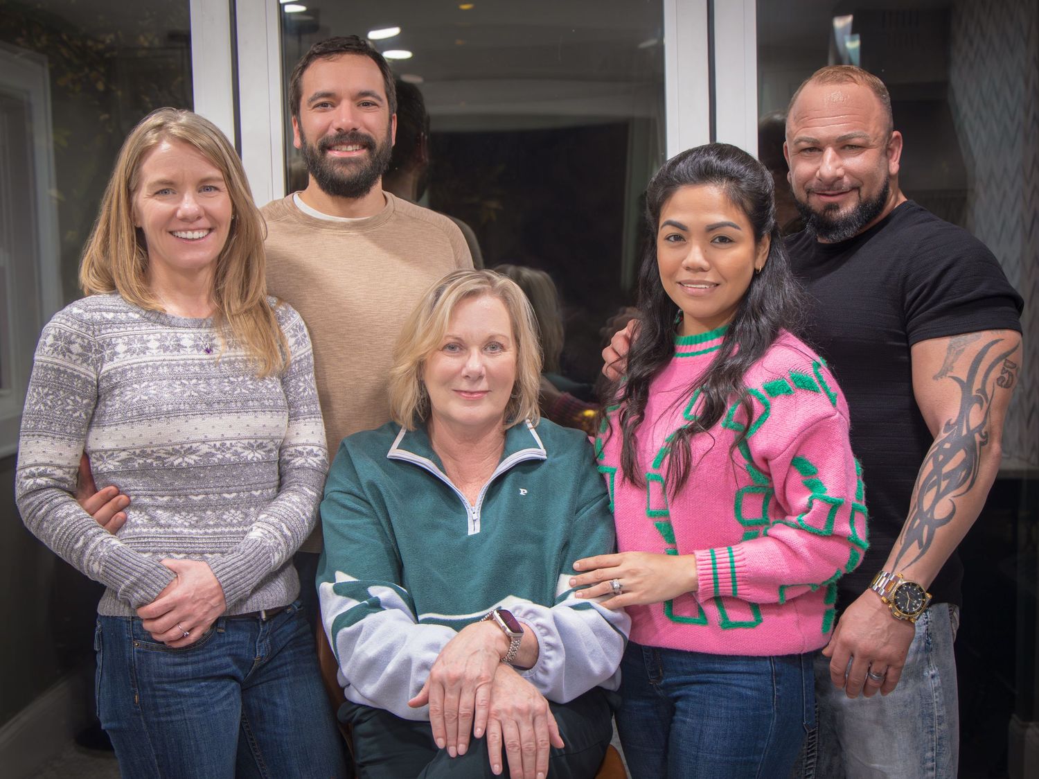 A group photo of six people standing together in casual attire against a light background.