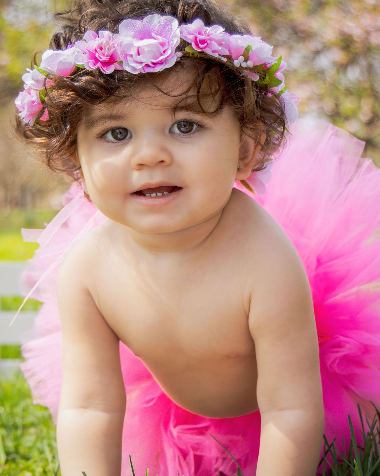 A pink tutu and floral crown create a dreamy springtime portrait against a blurred natural background.