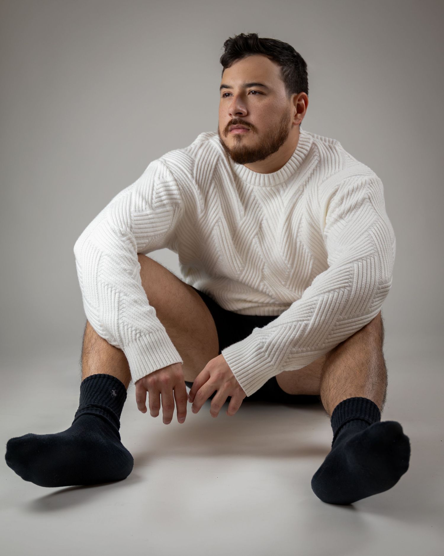 Artistic photo series showing a person in a white sweater and dark pants posing on the floor in various reclining positions.