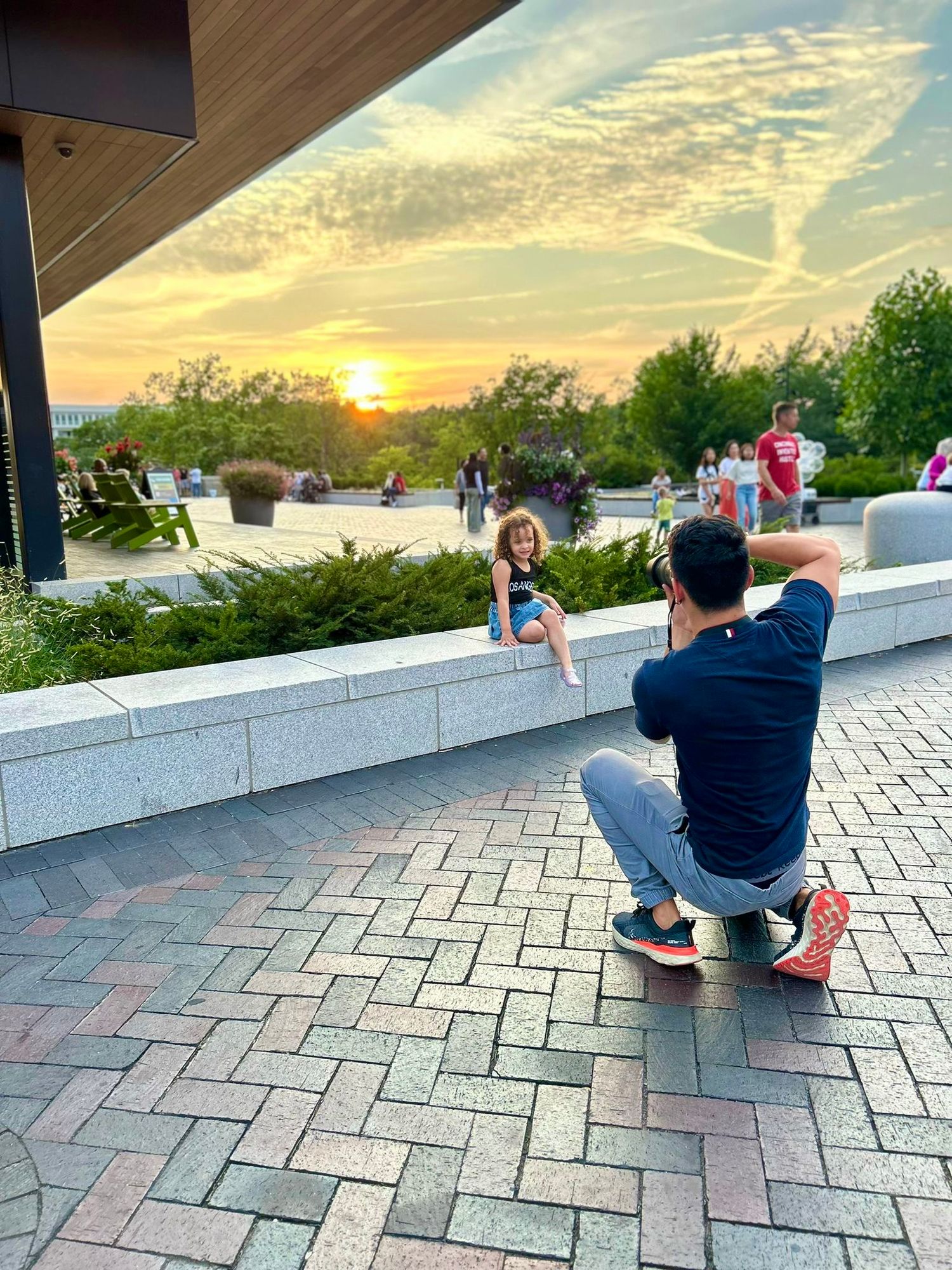 Photographer taking pictures during golden sunset on a paved outdoor terrace.