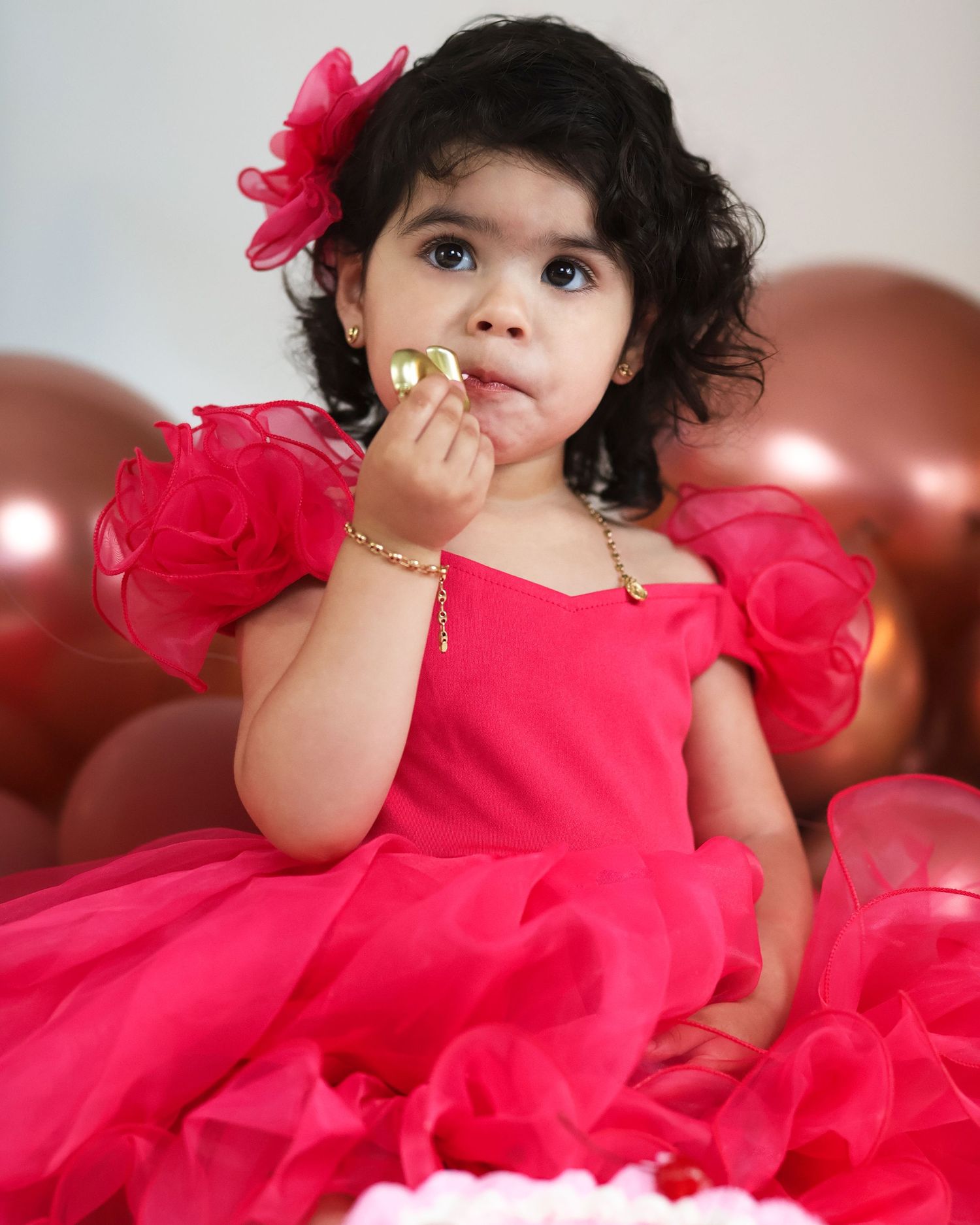 Puffy-sleeved pink dress against balloon backdrop during celebration.