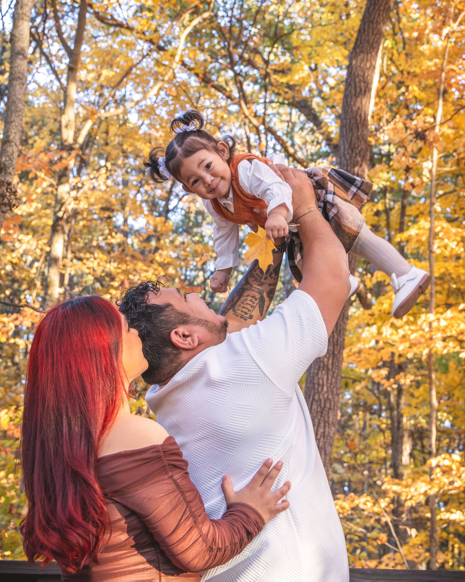 Playful family moment captured in autumn forest with golden leaves.