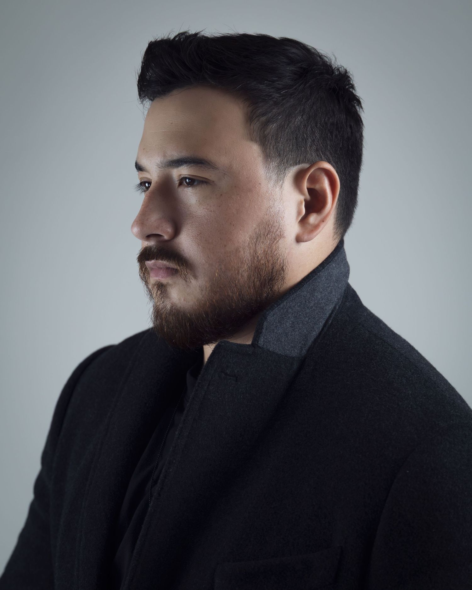 Profile views of a bearded man in a dark coat against a gray background show different angles and expressions.
