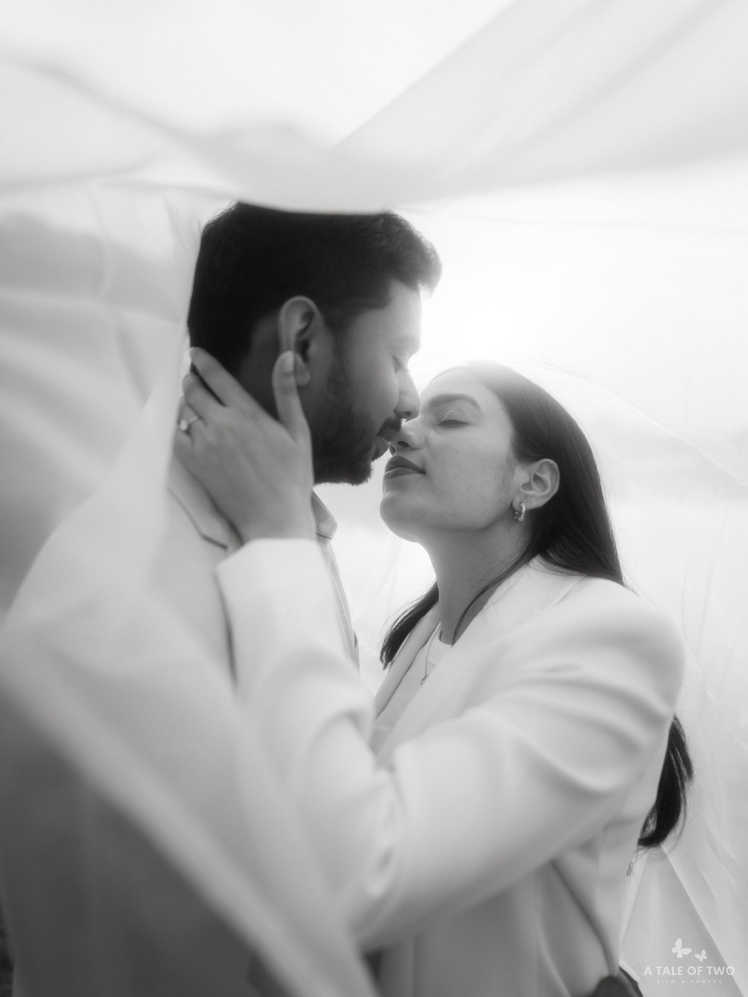 A romantic black and white photo sequence showing a tender kiss between a couple in white clothing.