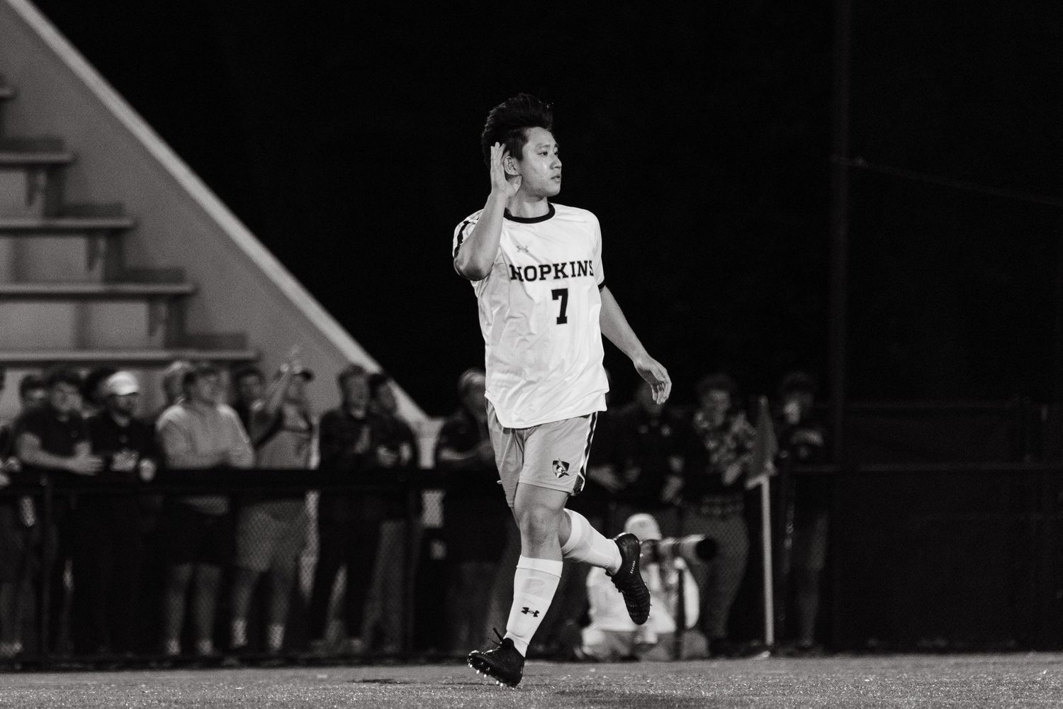 Soccer player in a white jersey with number 7 running on the field at night.