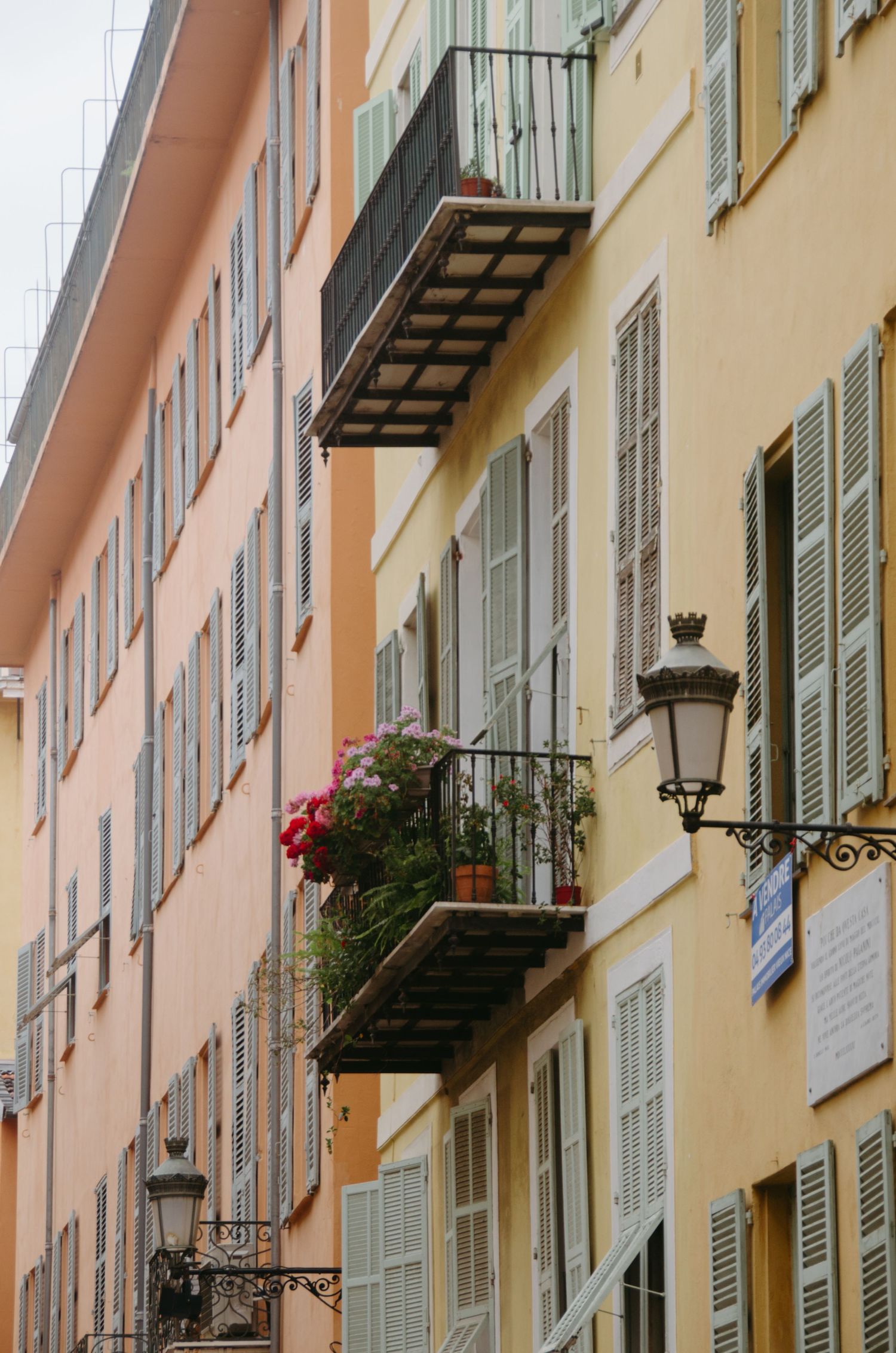 Colorful Mediterranean building facades with traditional shutters and ornate wrought iron balconies.