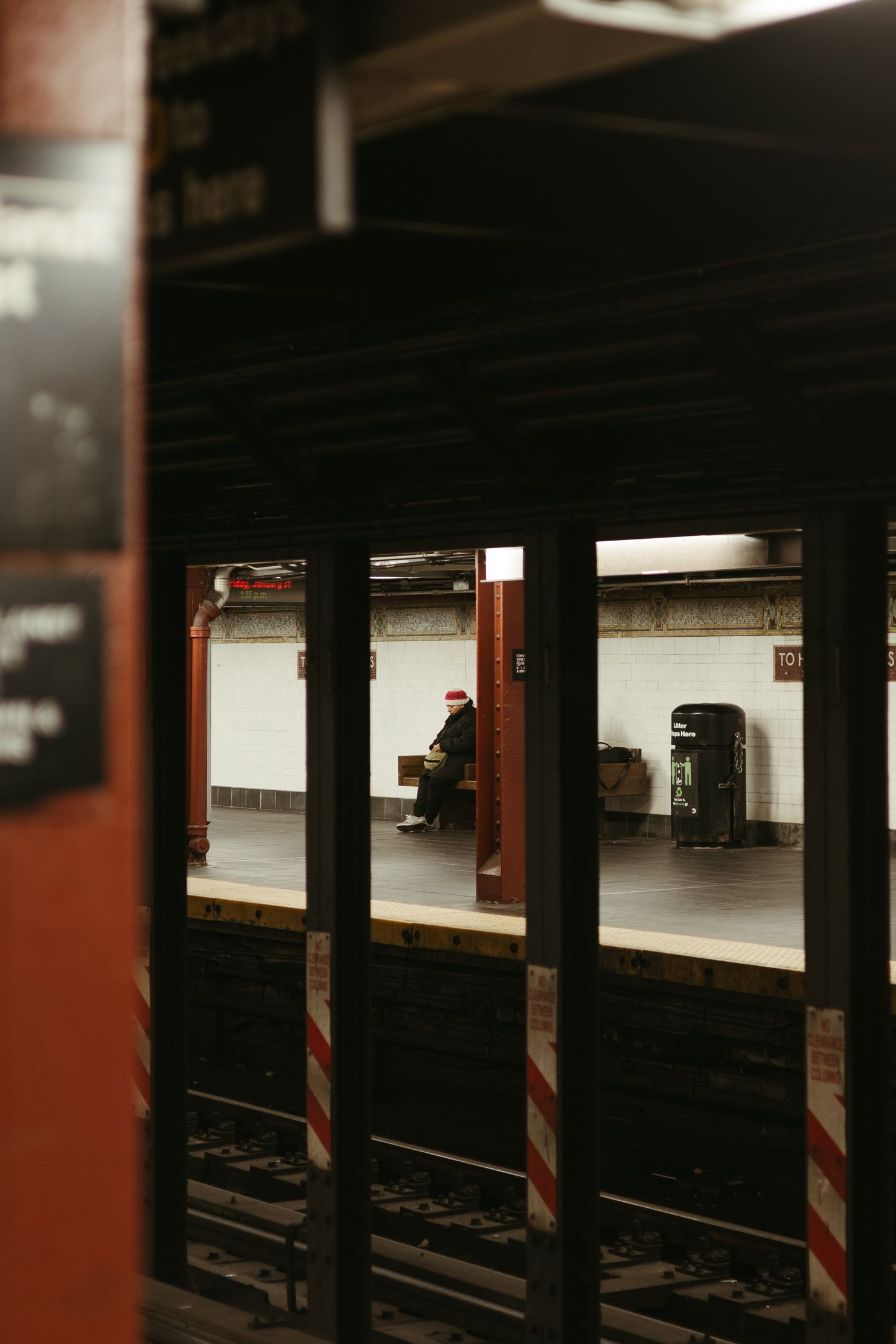 Empty subway platform with red columns and white walls stretches into darkness at night.