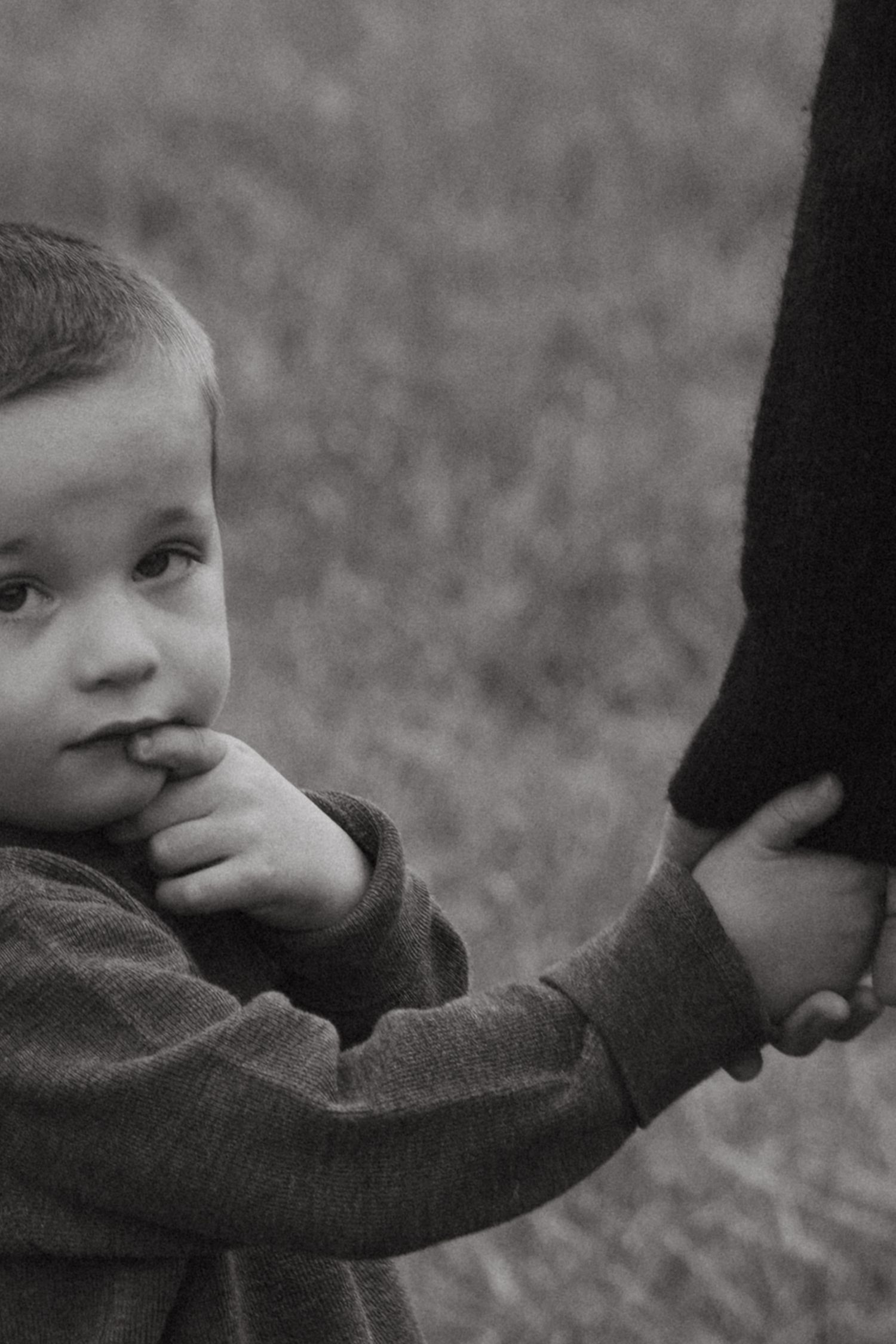Black and white artistic photo sequence showing a child's face gradually disappearing behind a sleeve or fabric.