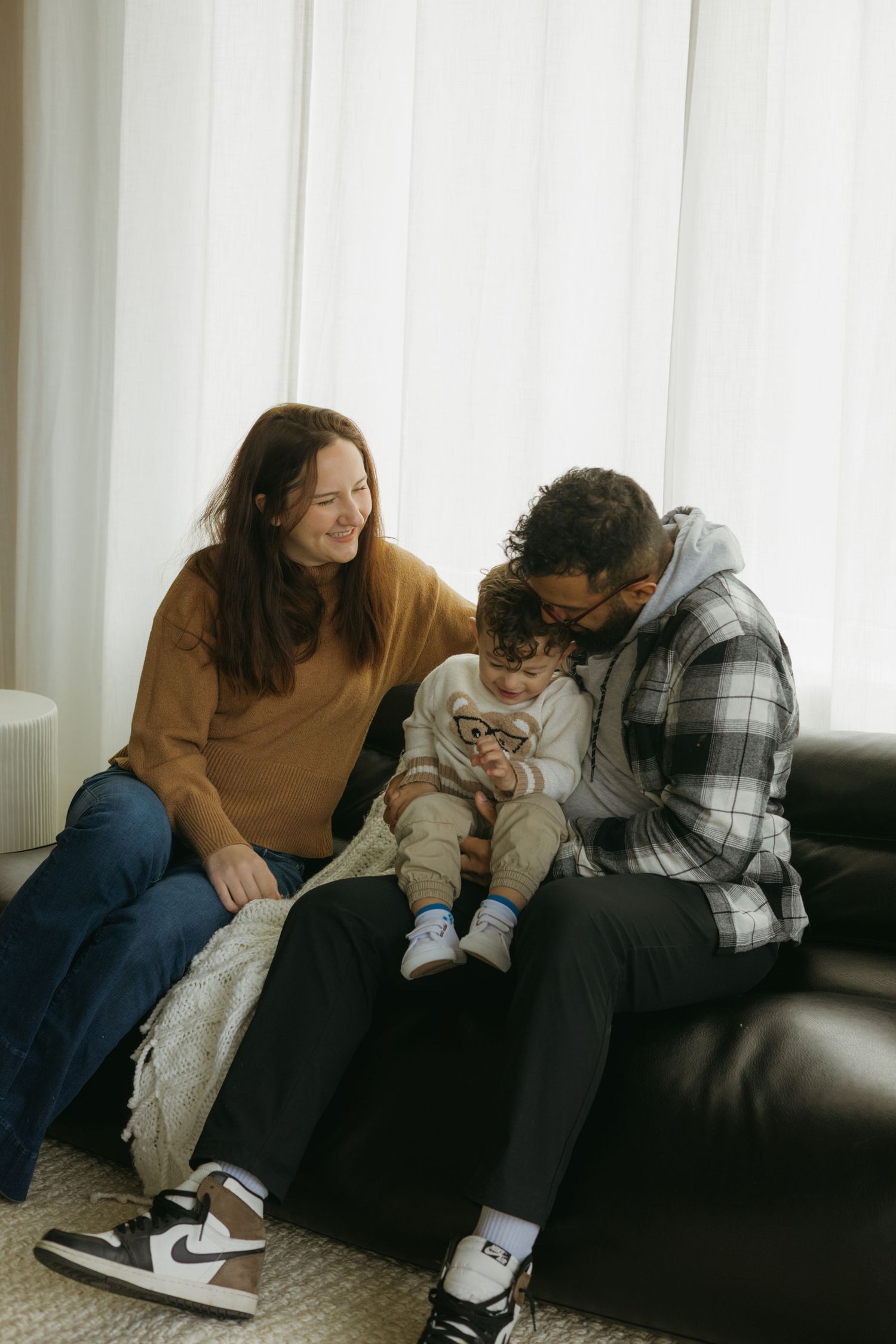Three candid photos show people relaxing together on a dark couch in a bright room with white curtains.