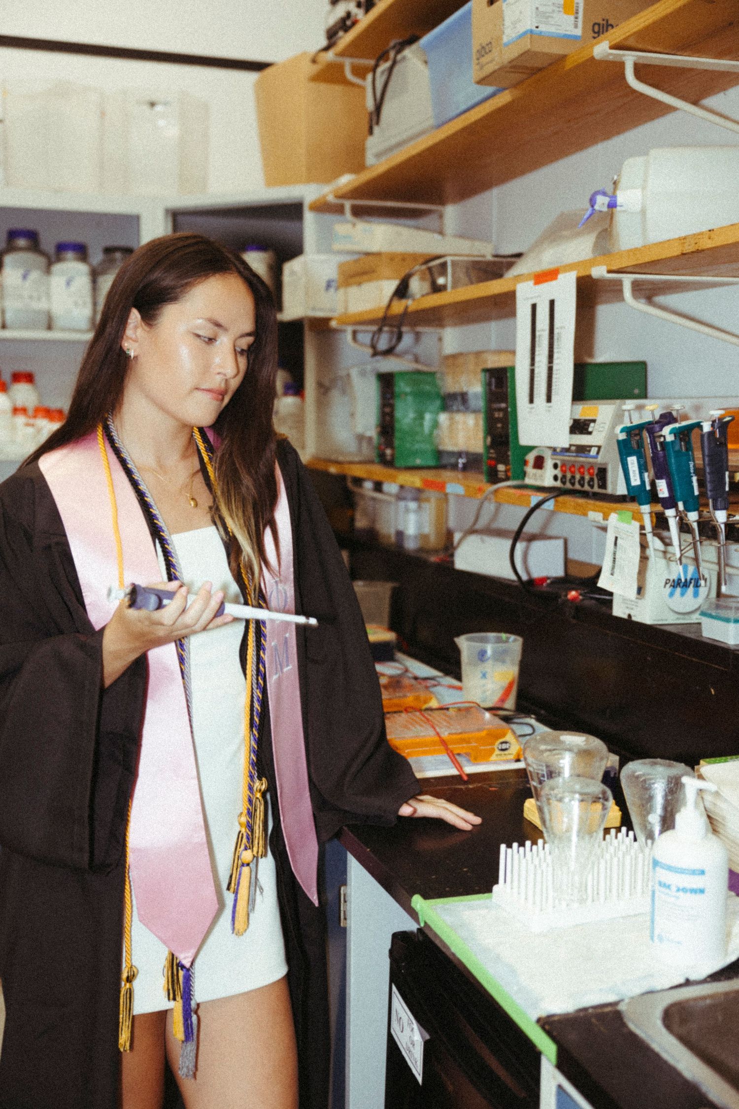 Scientist working in laboratory setting with test tubes and research equipment on wooden shelves.