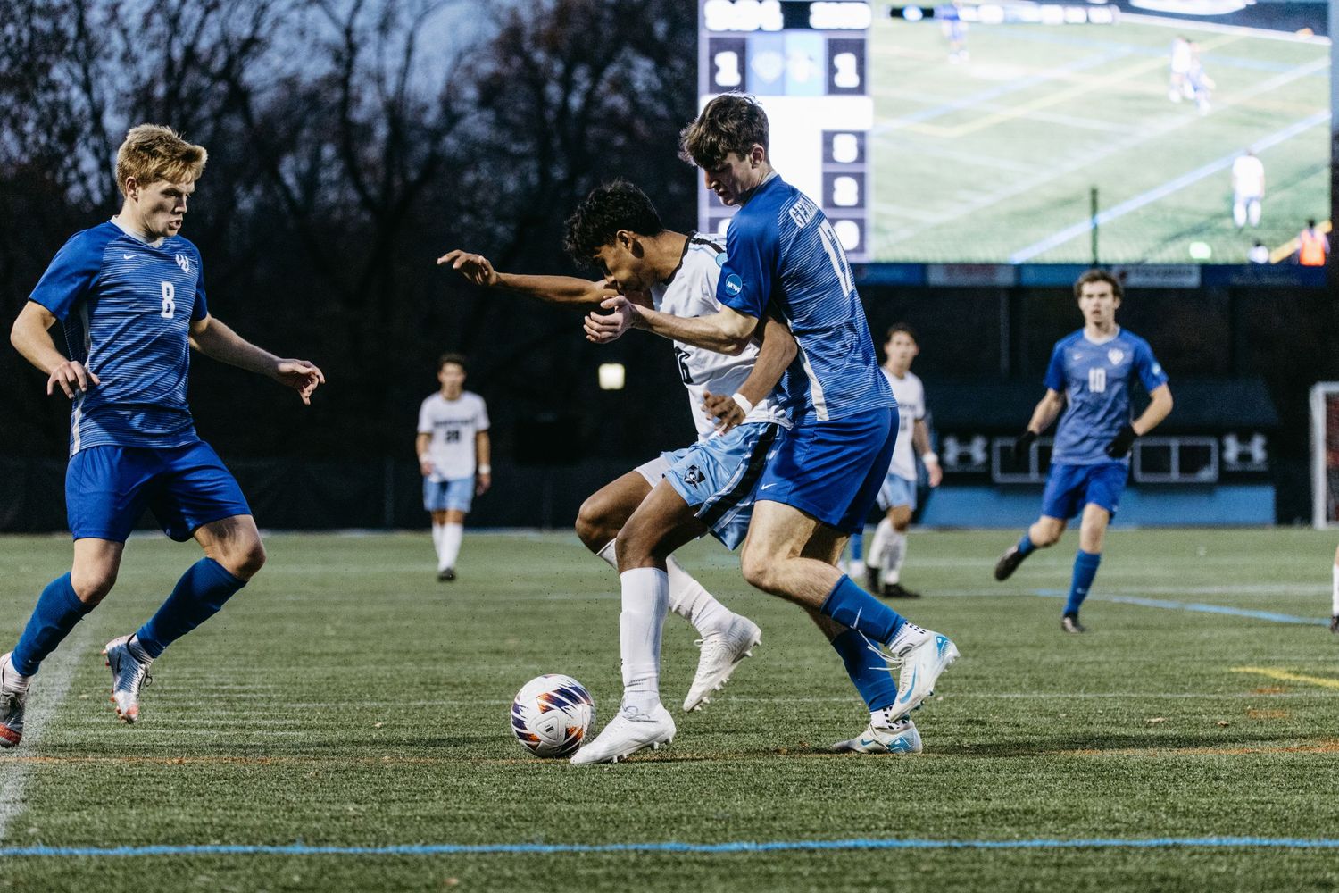 Soccer players battle for ball control during intense match on turf field.