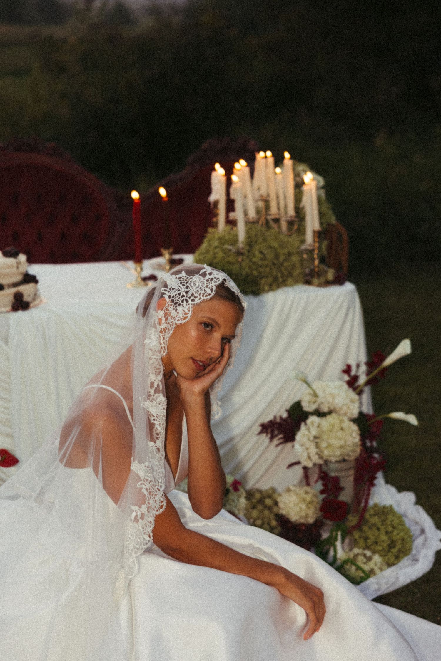 An elegant wedding table setting features white candles, white linens and floral arrangements at sunset.