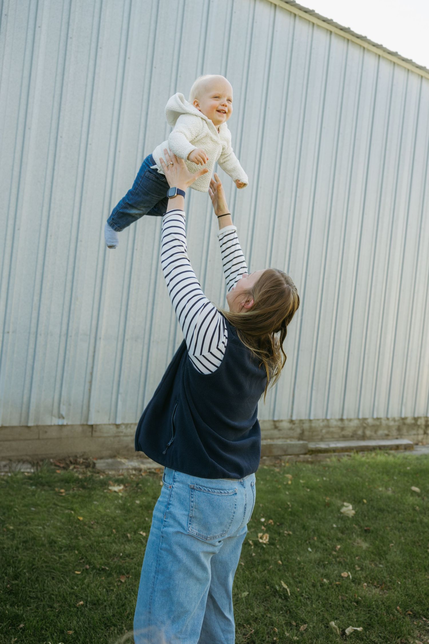 A series of four sequential photos showing someone playfully tossing a small baby in the air against a metal wall backdrop.