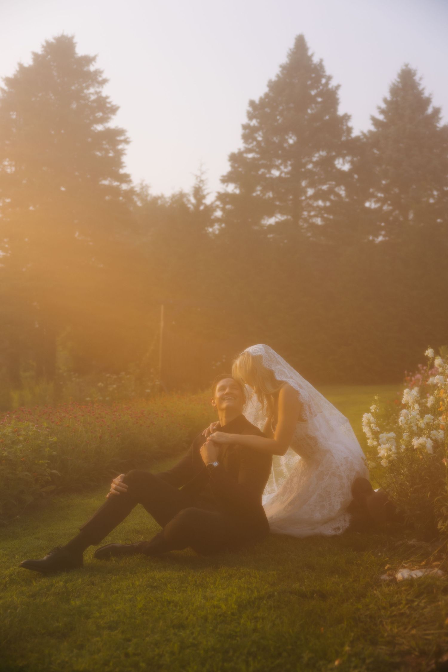 A bride on a grassy hill at golden hour with trees in the background.